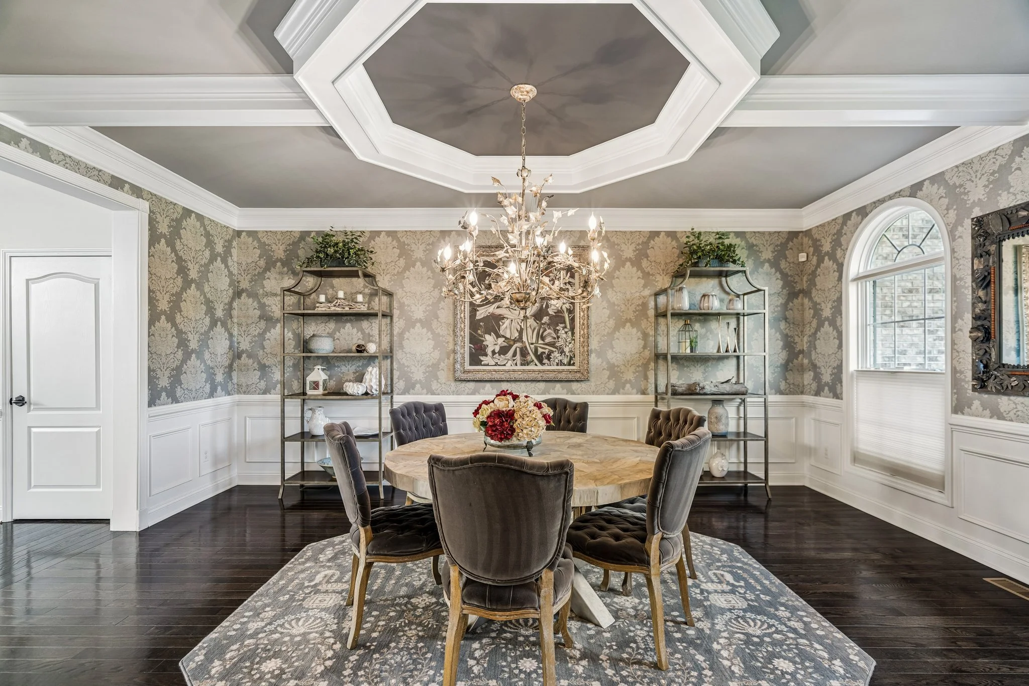 Formal dining room with a coffered octagonal ceiling, chandelier, round table, and wainscoting