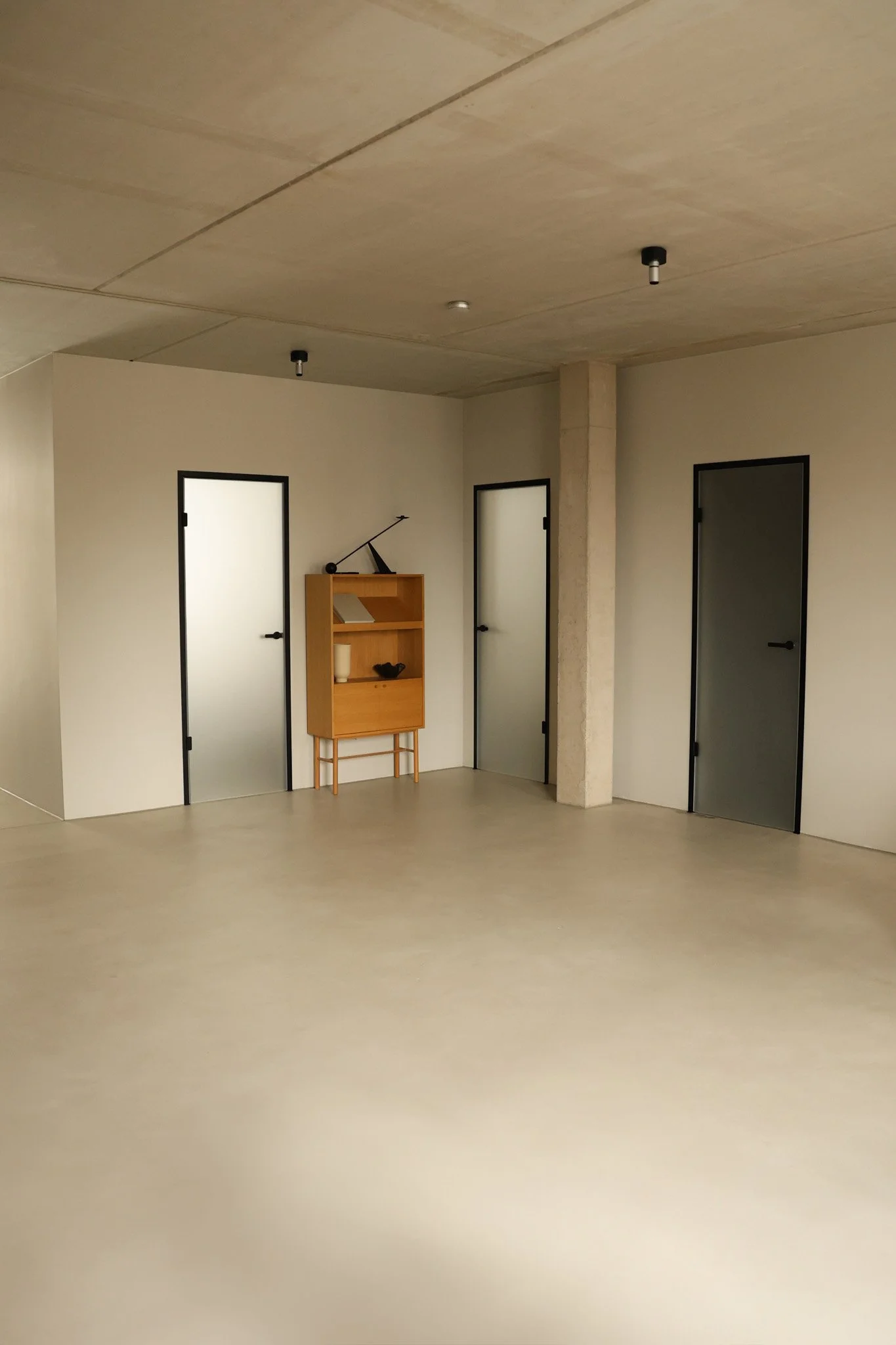 Ein halb geöffnetes weißes Tür in einem dunklen Raum, durch die Sonnenlicht auf die Wand hinter der Tür scheint.