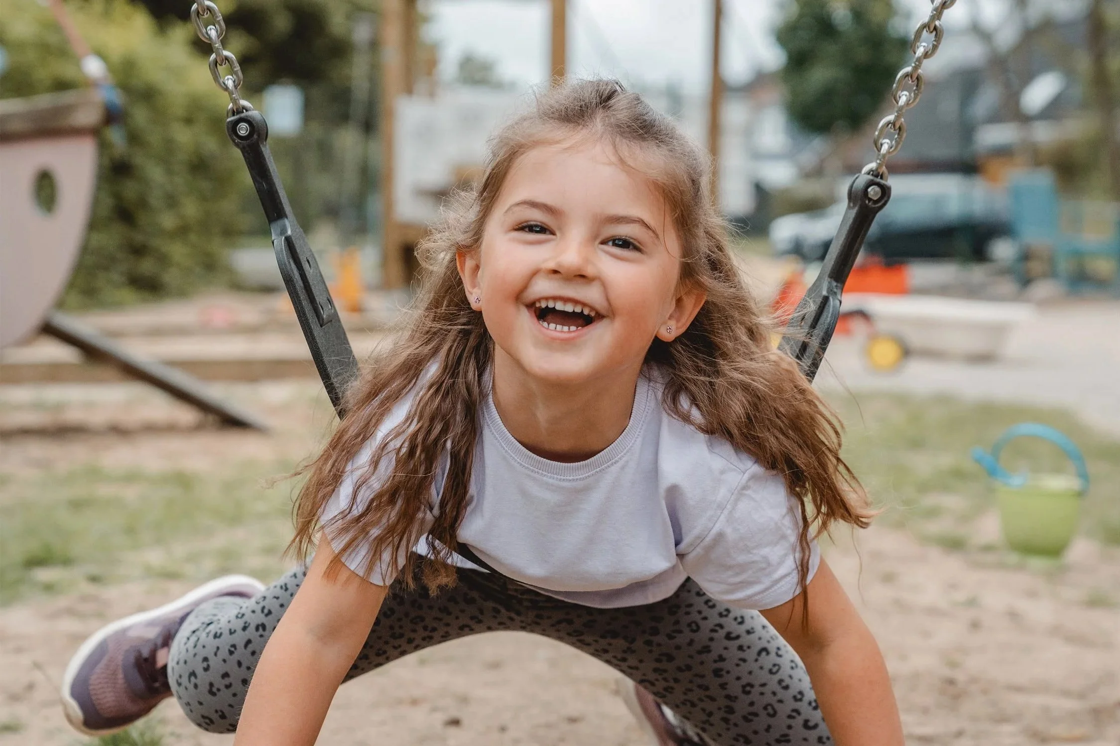 Mädchen schaukelt auf ihrem Bauch und lacht in die Kamera