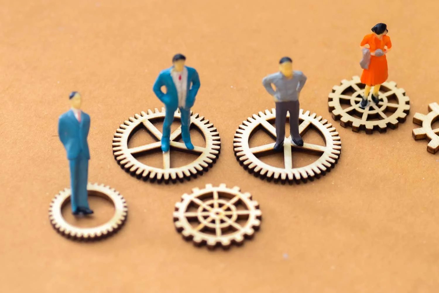 Miniature people stand on separated gears