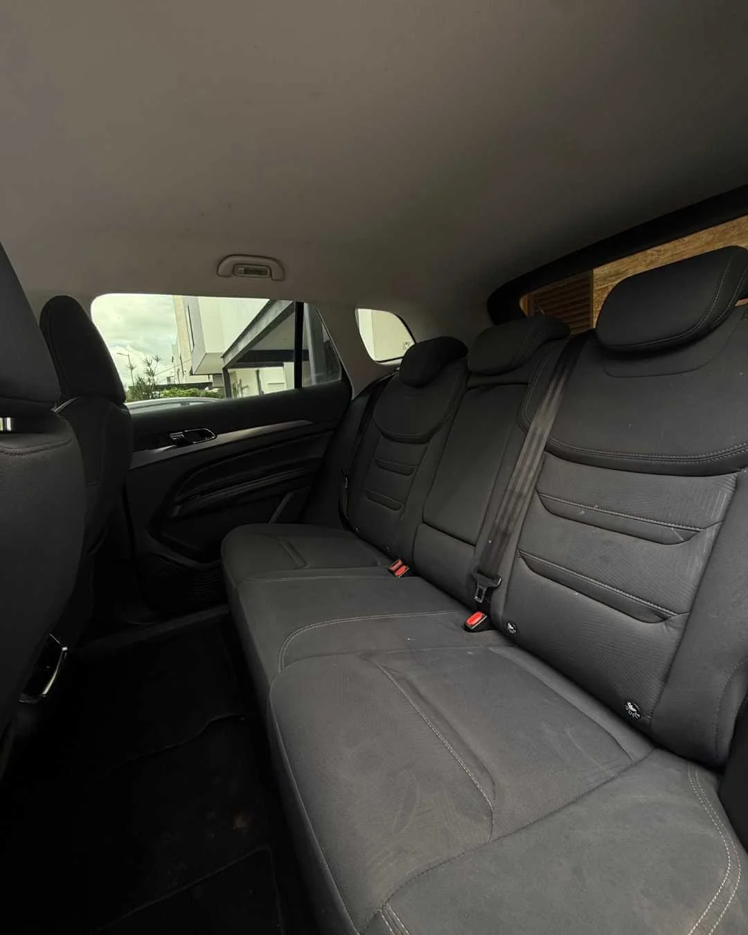 Asiento trasero de automóvil con cinturones de seguridad y cabezales ajustables, vista desde el interior del vehículo.