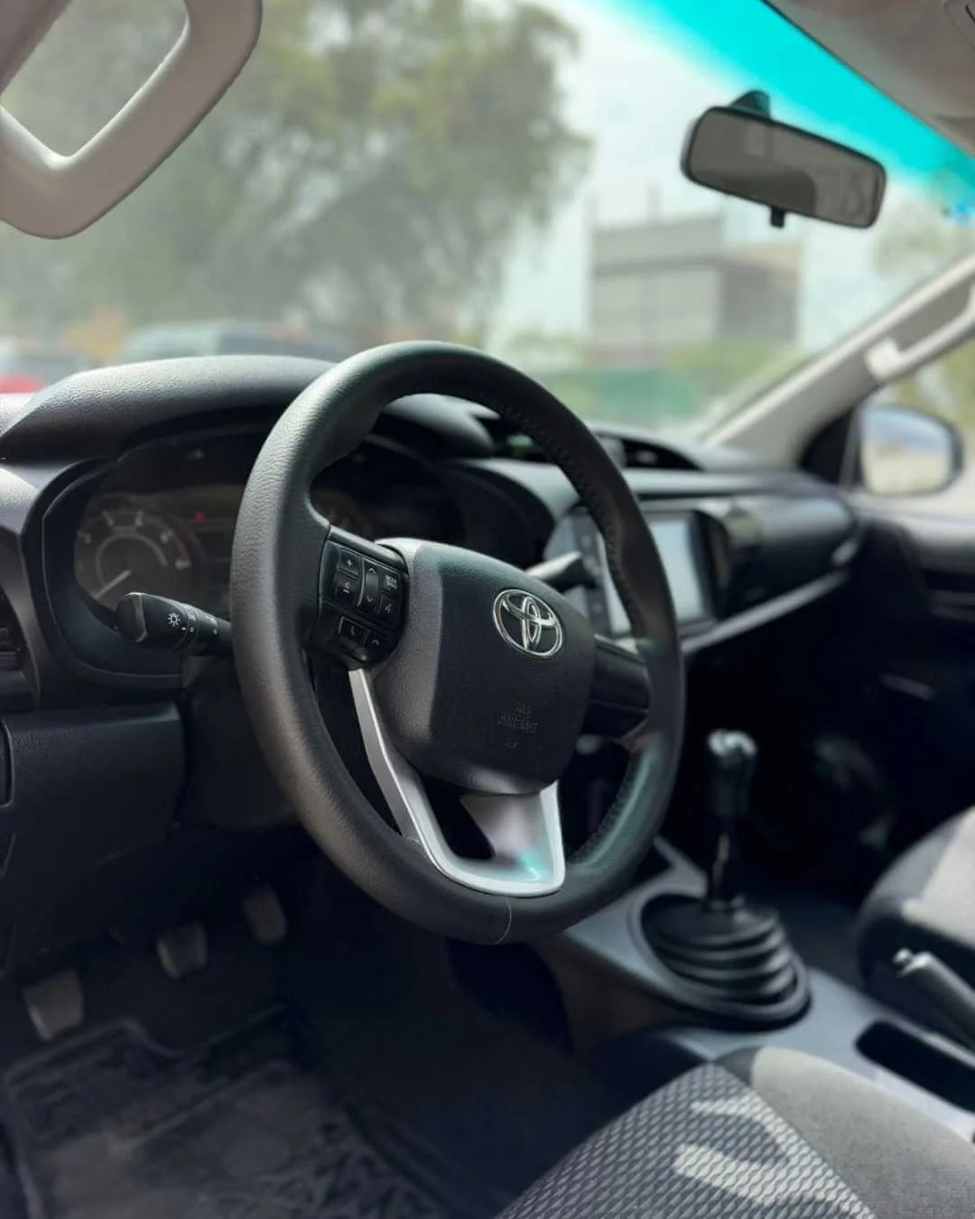 Interior de un automóvil Toyota, vista del volante, tablero, palanca de cambios y espejos laterales.