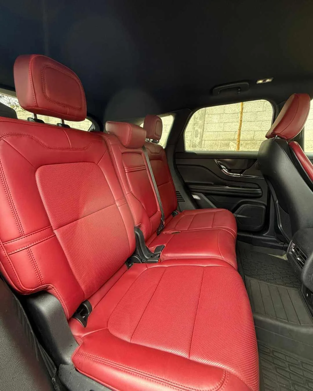 Asientos traseros de auto tapizados en piel roja en un vehículo.