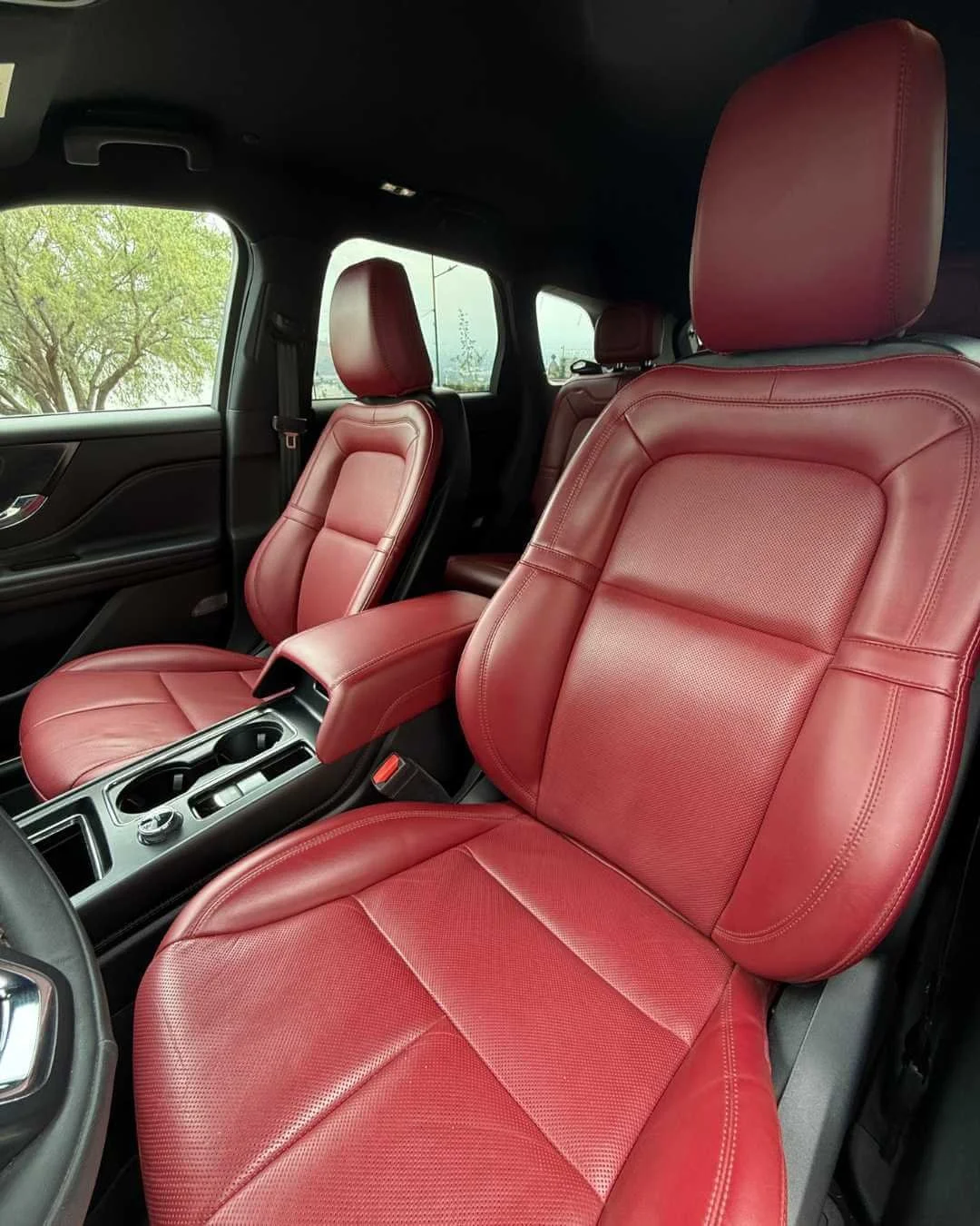 Asientos delanteros del auto con tapicería de cuero rojo.