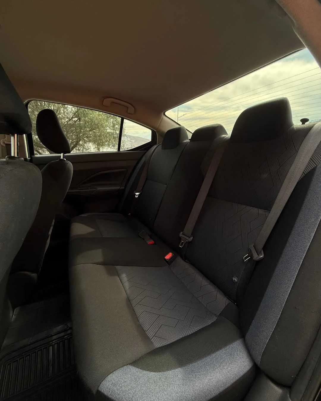 Asientos traseros de un vehículo, con cinturones de seguridad, en un coche de color oscuro.