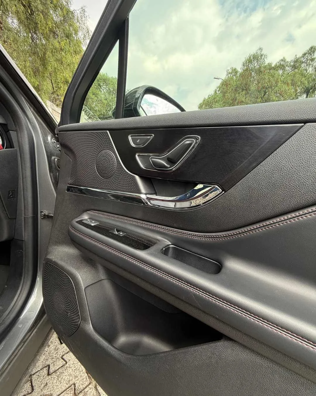 Puerta de coche moderna con control de ventanas, asientos ajustables y altavoz.