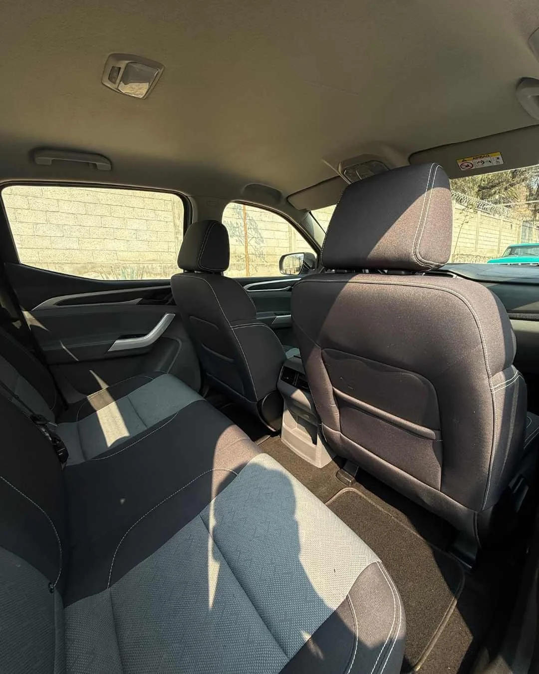 Interior de un automóvil, asientos delanteros y traseros, ventanas y portavasos.