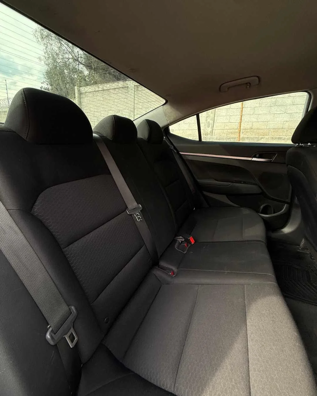 Asiento trasero de coche con three asientos y cinturones de seguridad.