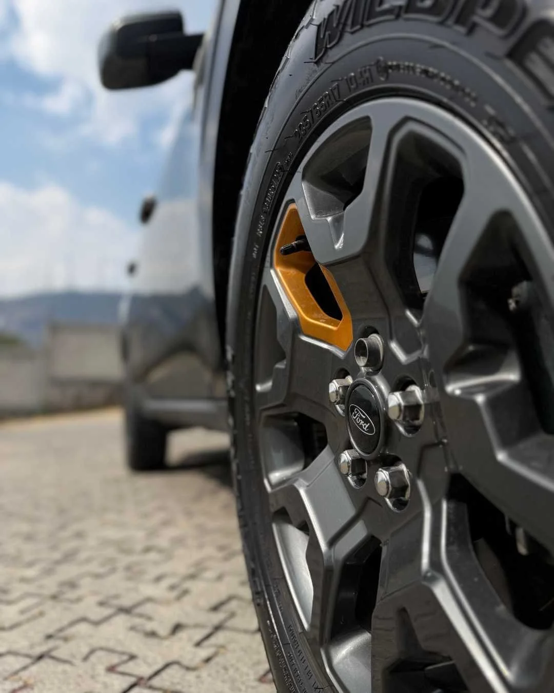 Rueda de auto Ford con diseño moderno, en un entorno exterior con cielo despejado.