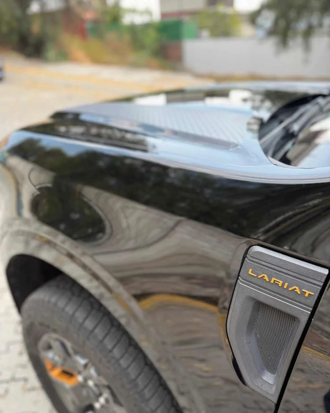 Cerca de la rueda y la parte lateral de un vehículo negro de marca Larriet, con un espejo retrovisor adjunto.