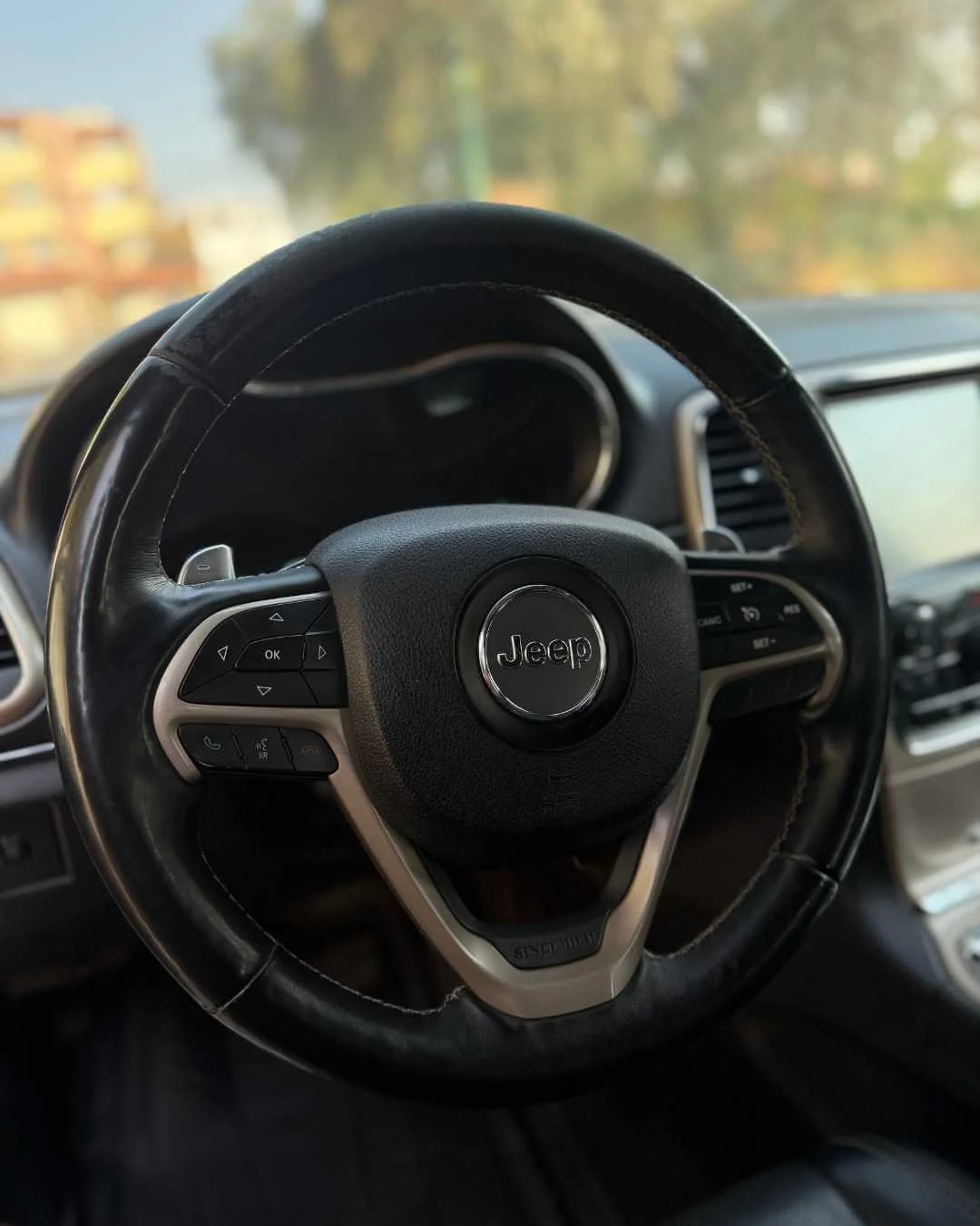 Volante de un coche Jeep negro con controles en el lado izquierdo, vista desde el interior del vehículo.