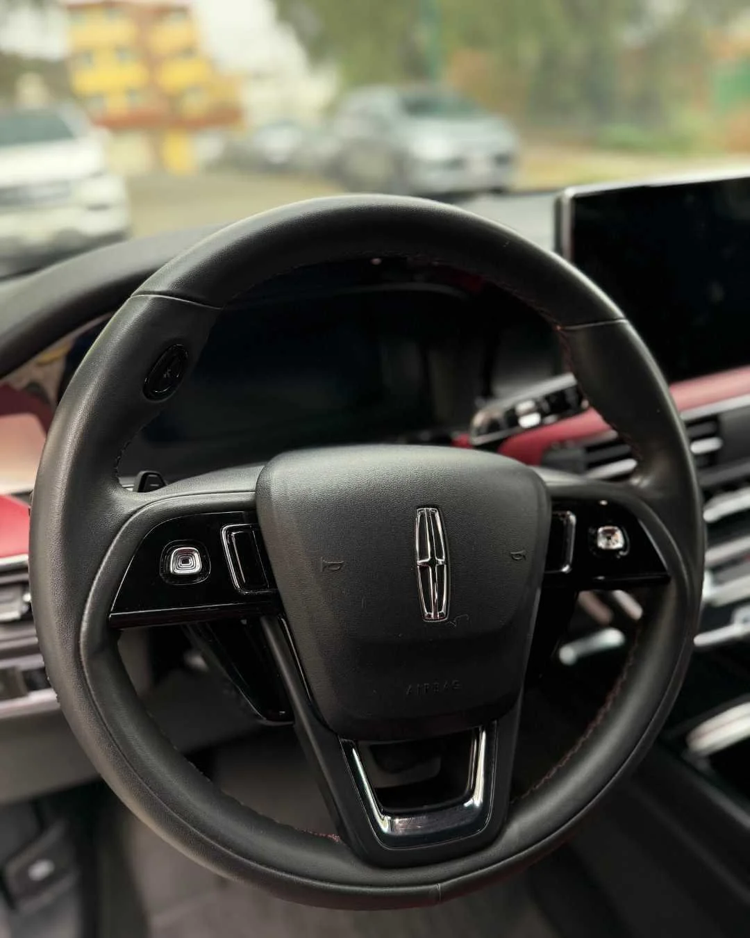Volante de automóvil con logotipo de Lincoln en el centro, interior de vehículo moderno, vista desde el conductor.