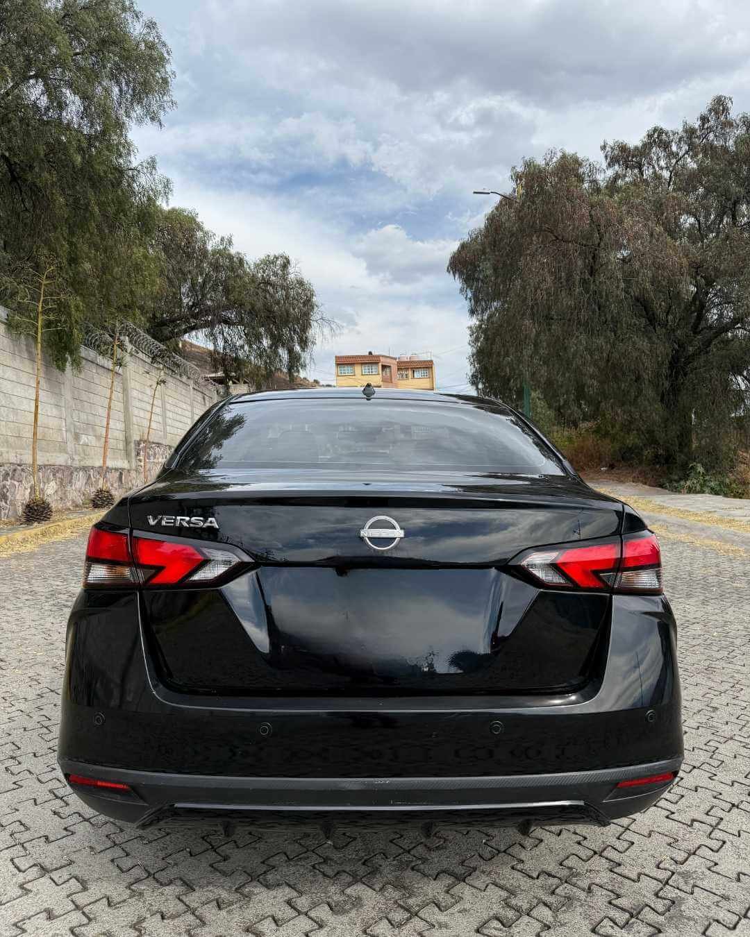 Automóvil negro modelo Opel Versa estacionado en un camino de piedra