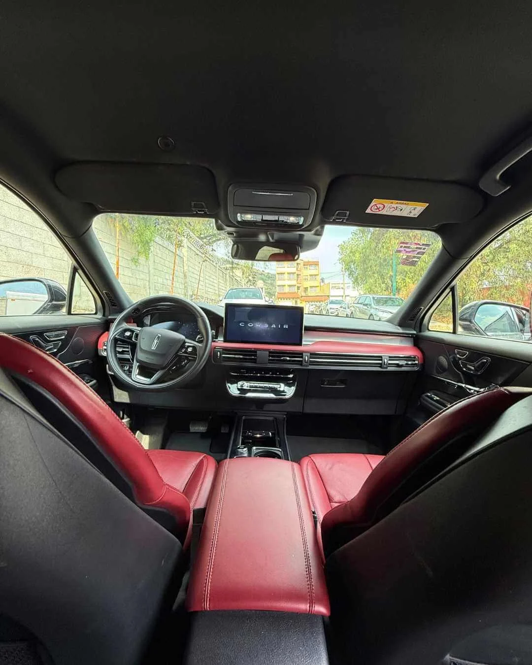 Vista del interior de un automóvil, asiento trasero en color rojo y coche en movimiento.