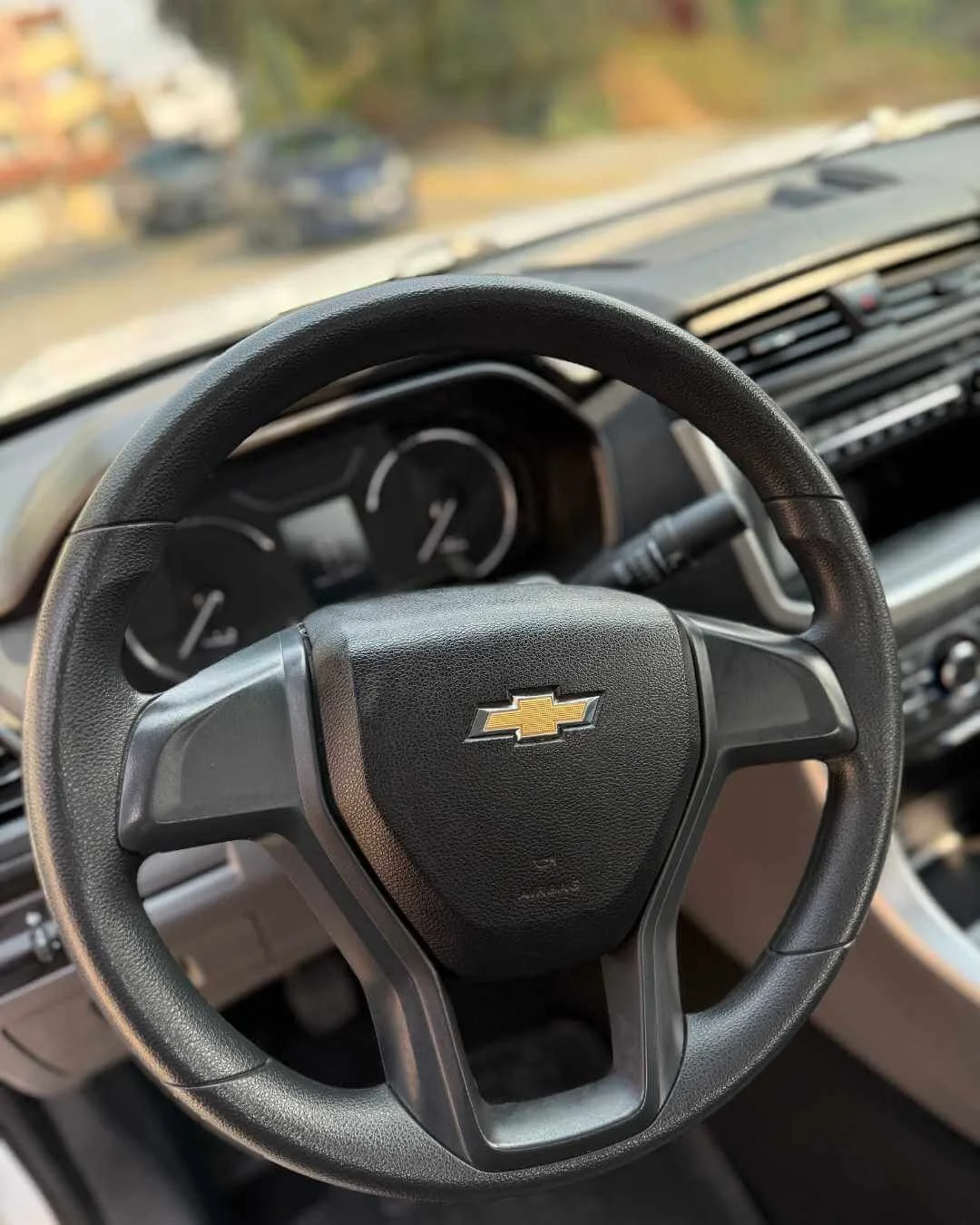 Volante de coche con logotipo de Chevrolet en el centro, vista del tablero y el interior del vehículo.