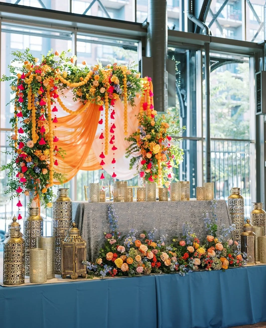 Layered with warm marigold orange, bright pink, and dusty blue, this Indian-inspired decor provided a show-stopping focal point for the sweetheart table! ⁠
⁠
Planning | ⁠@stylearchitectsweddings⁠
Venue | @renaissancempls⁠
Photography | @maritwilliams