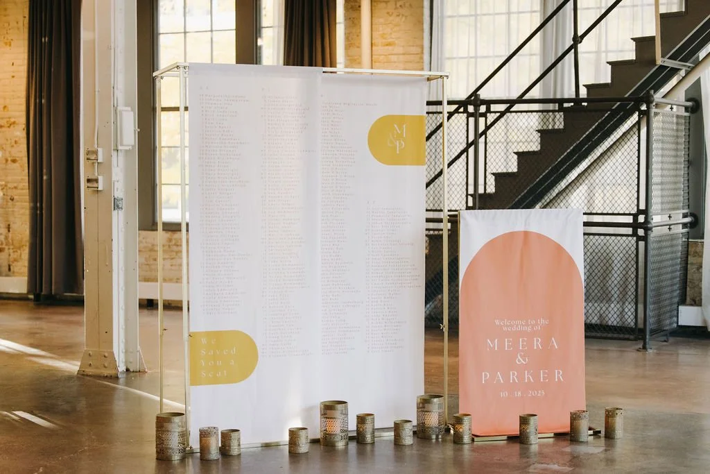 Wedding seating chart with candles in a well-lit industrial-style venue.