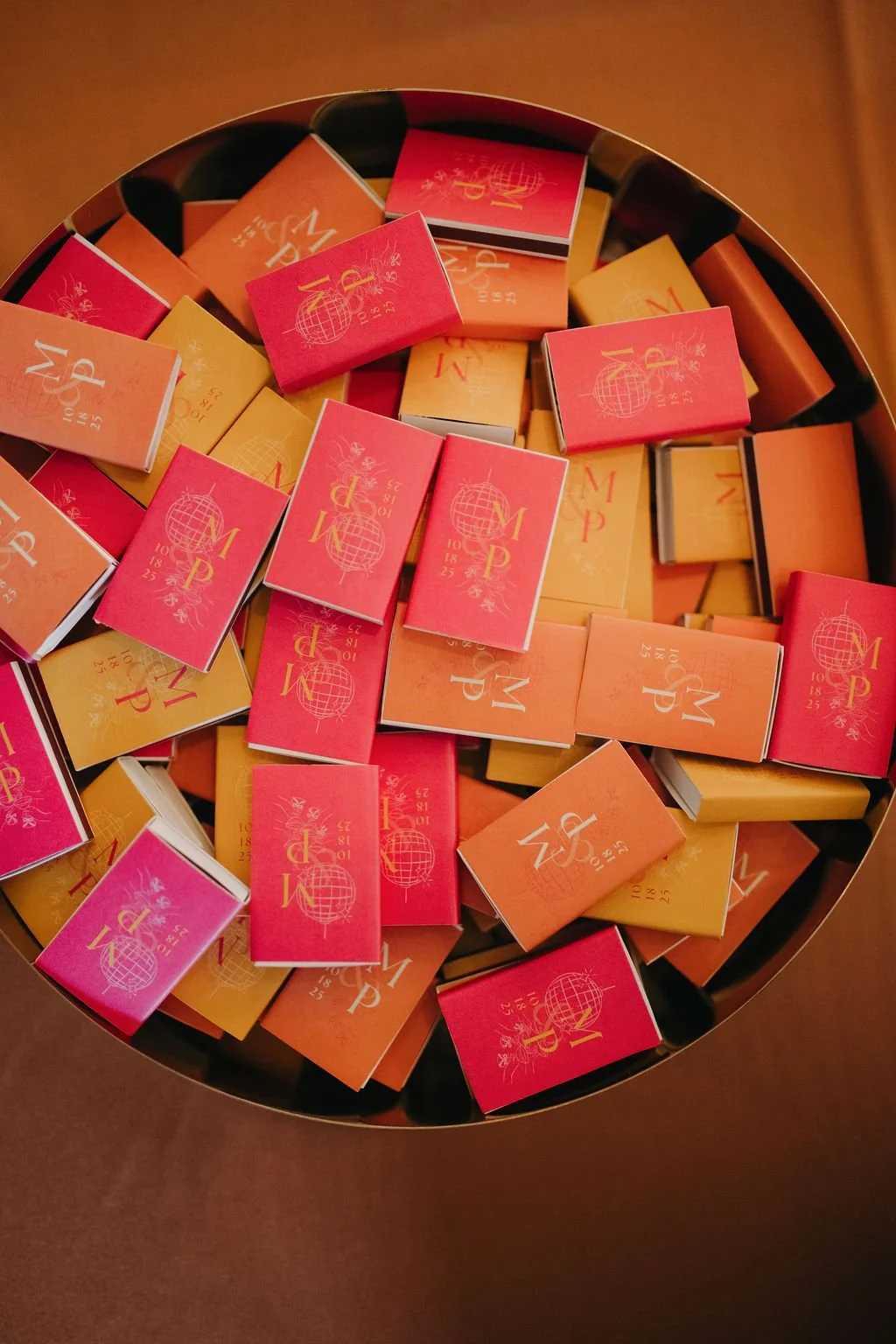 A round container filled with colorful matchboxes in shades of pink, orange, and yellow, featuring a globe design and the word 'MAP' on each.