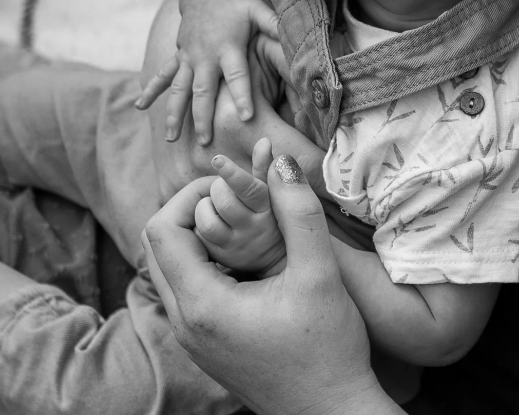 Een close-up van een volwassene die een jong kind vasthoudt en troost, in zwart-wit.