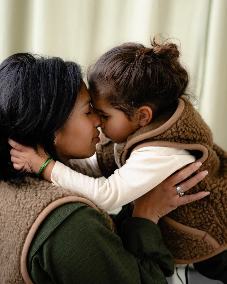 Twee vrouwen die hun voorhoofden tegen elkaar drukken, een jonge meisje knuffelt een vrouw.