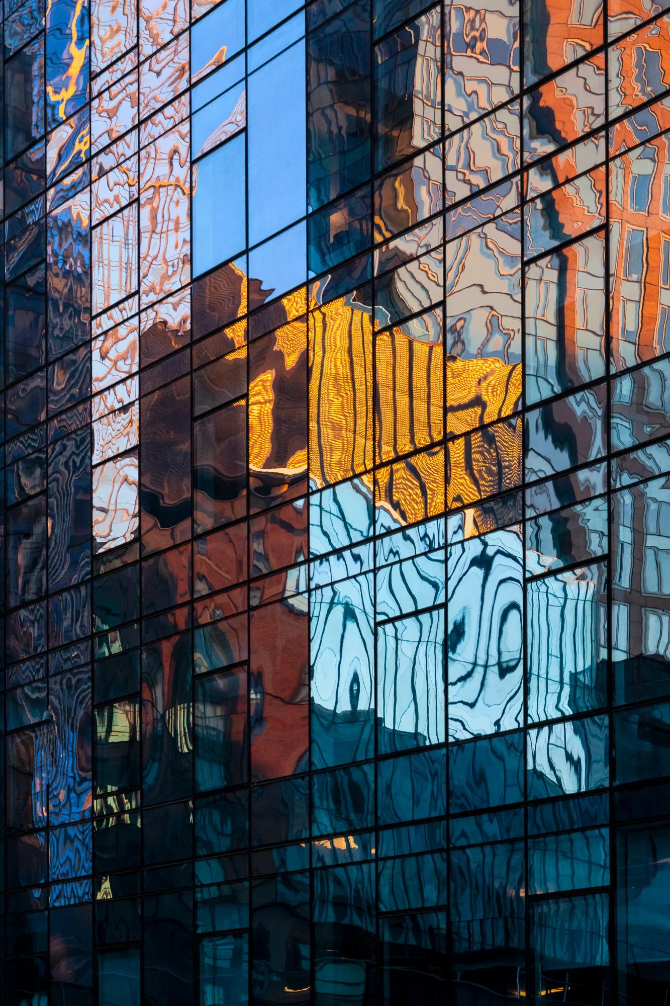 Windows and reflections create a layered grid in which surface, depth, and structure become difficult to separate.