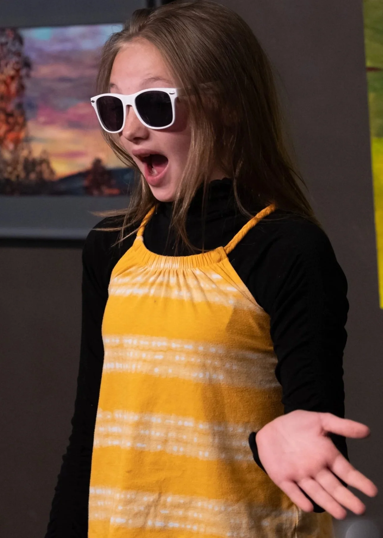Girl wearing sunglasses and a yellow and black outfit, expressing surprise.