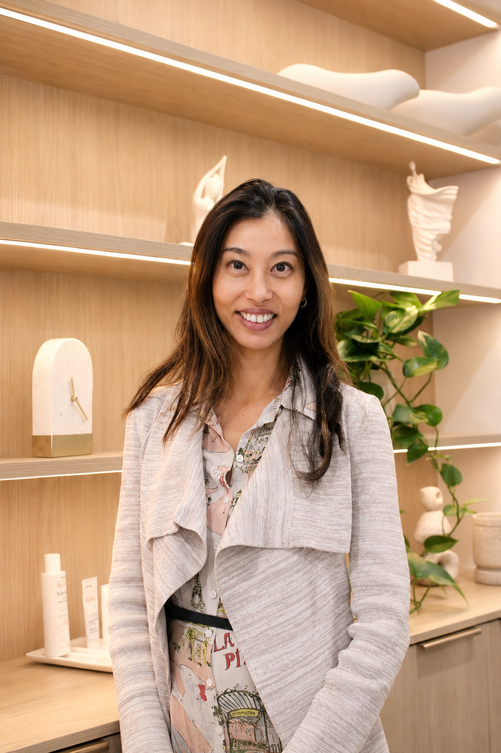 A woman with long dark hair wearing glasses & beige long jacket