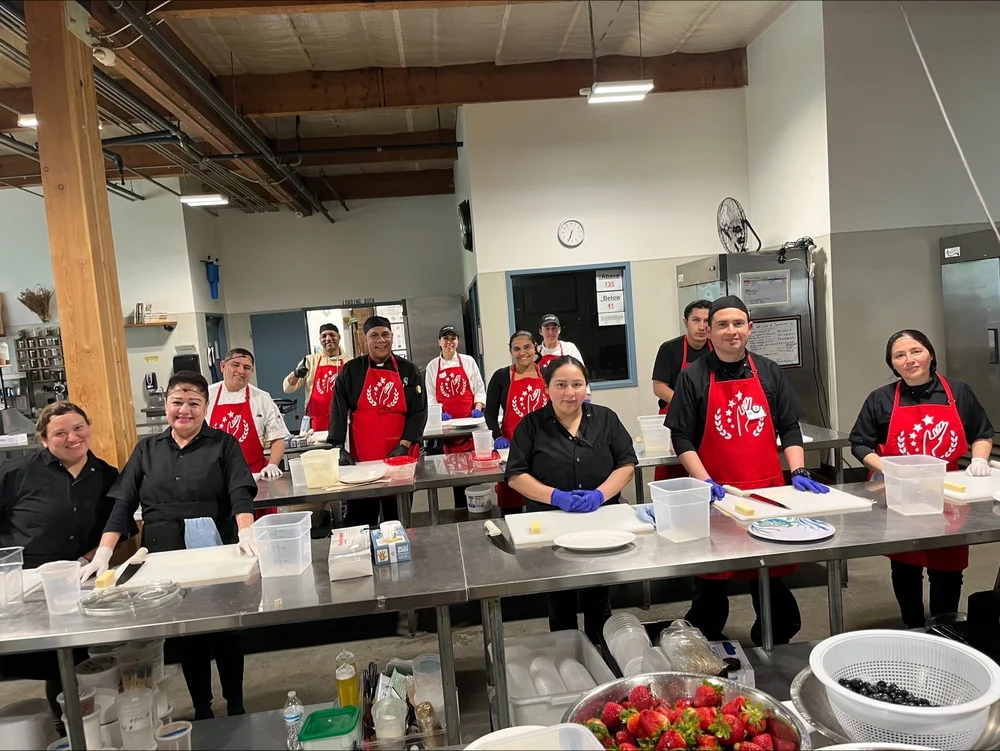 Estudiantes de cocina reunidos en la cocina de capacitación del programa