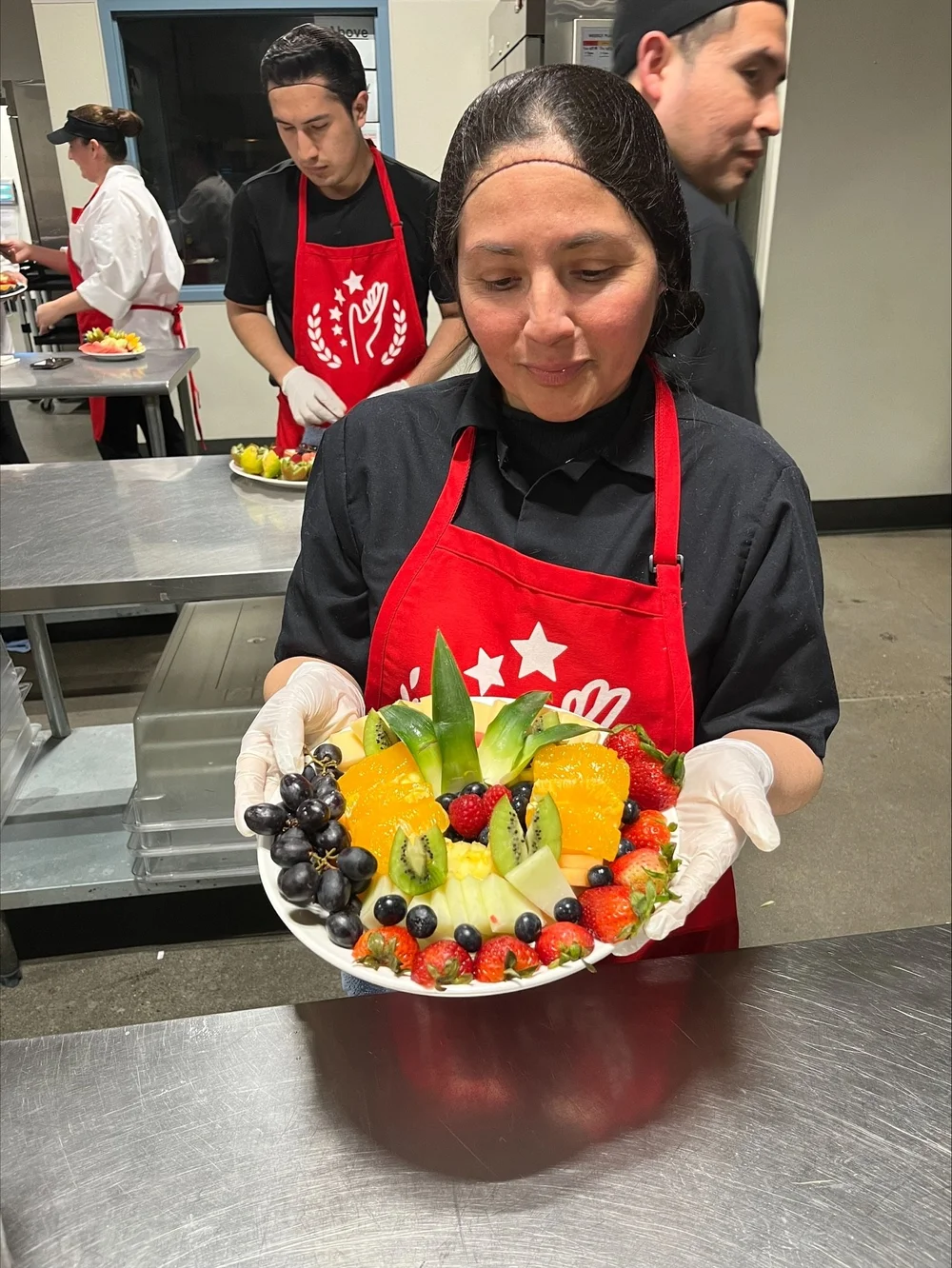 Una participante sonríe mientras sostiene una bandeja de frutas que ella misma preparó
