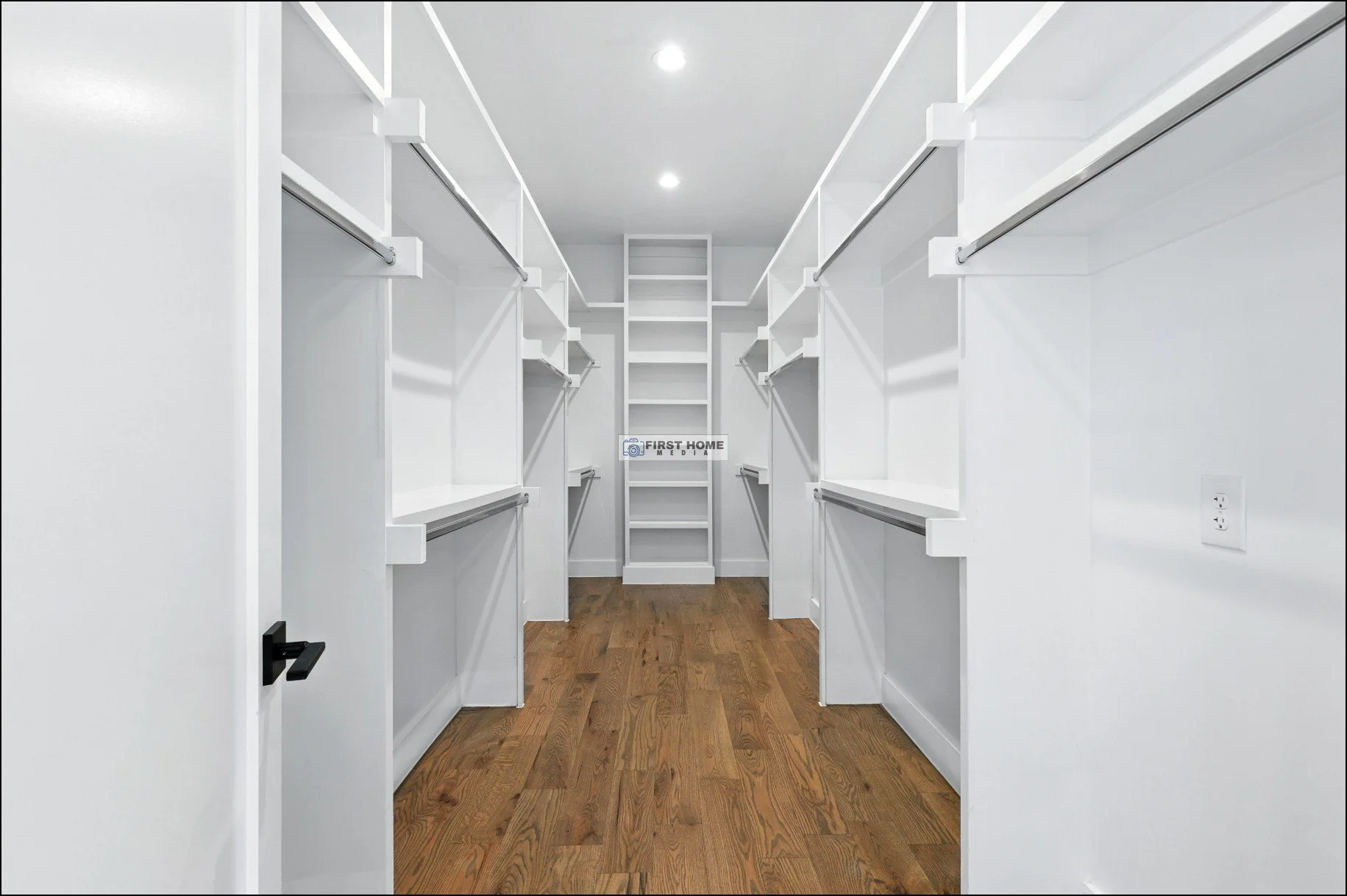 Walk-in closet with white shelving and hanging rods, hardwood flooring, and recessed lighting.