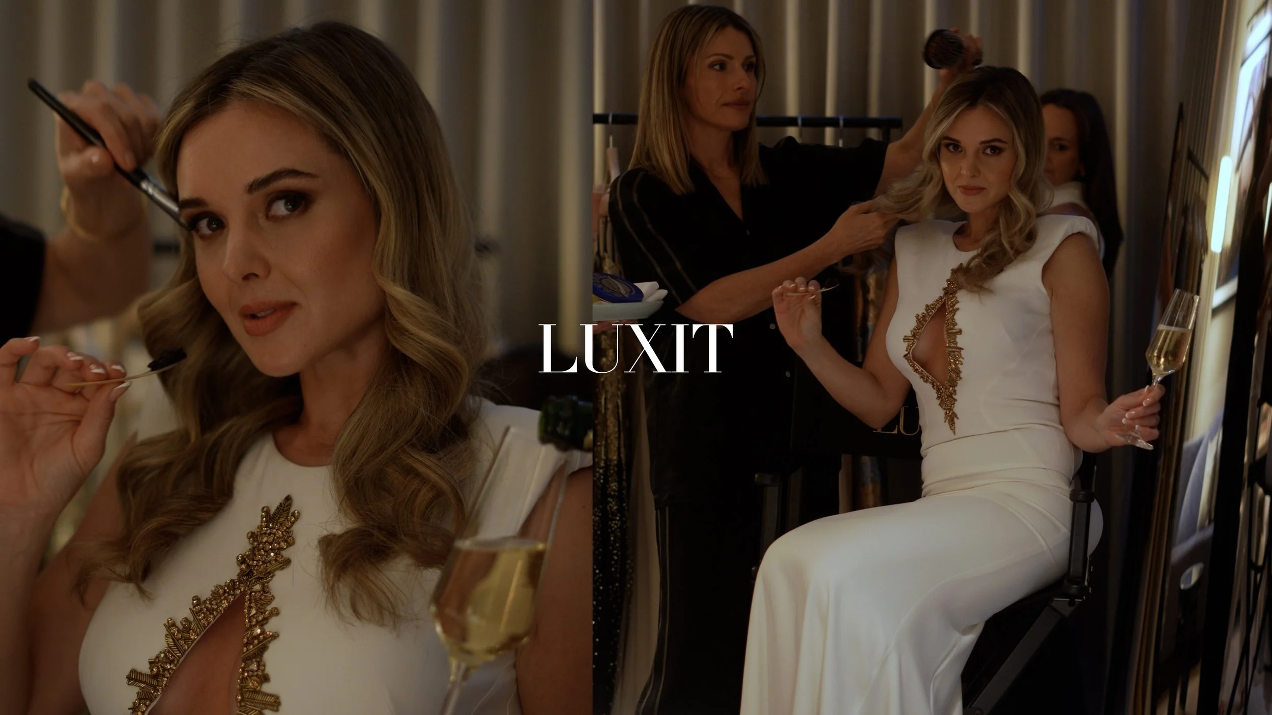 A woman with long blonde hair, wearing a white dress with gold embellishments, is getting her hair styled by a stylist in a dressing room. She holds a glass of champagne in one hand and is looking at the camera.
