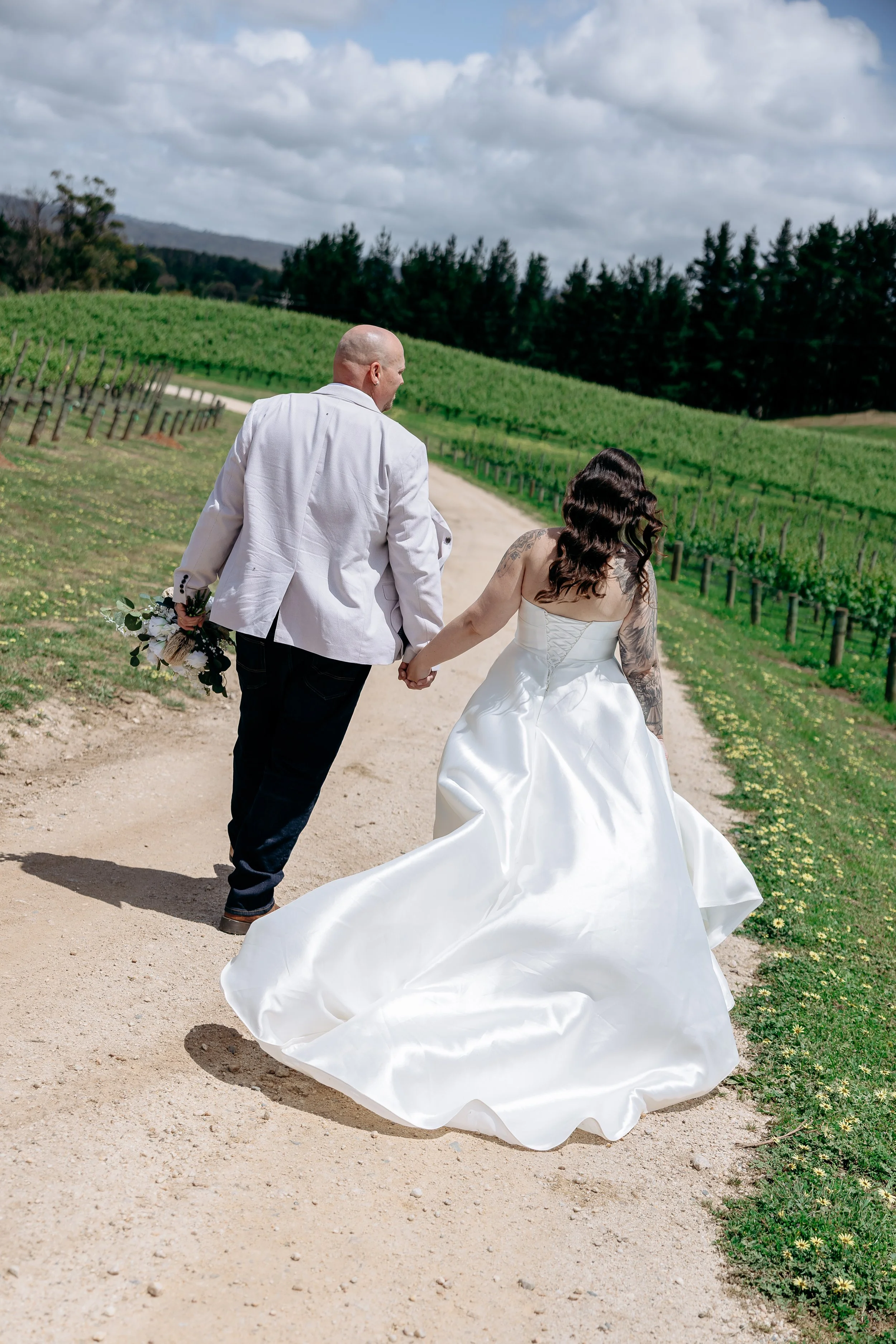 Bride and groom walking hand in hand through a South Australian vineyard on their wedding day.