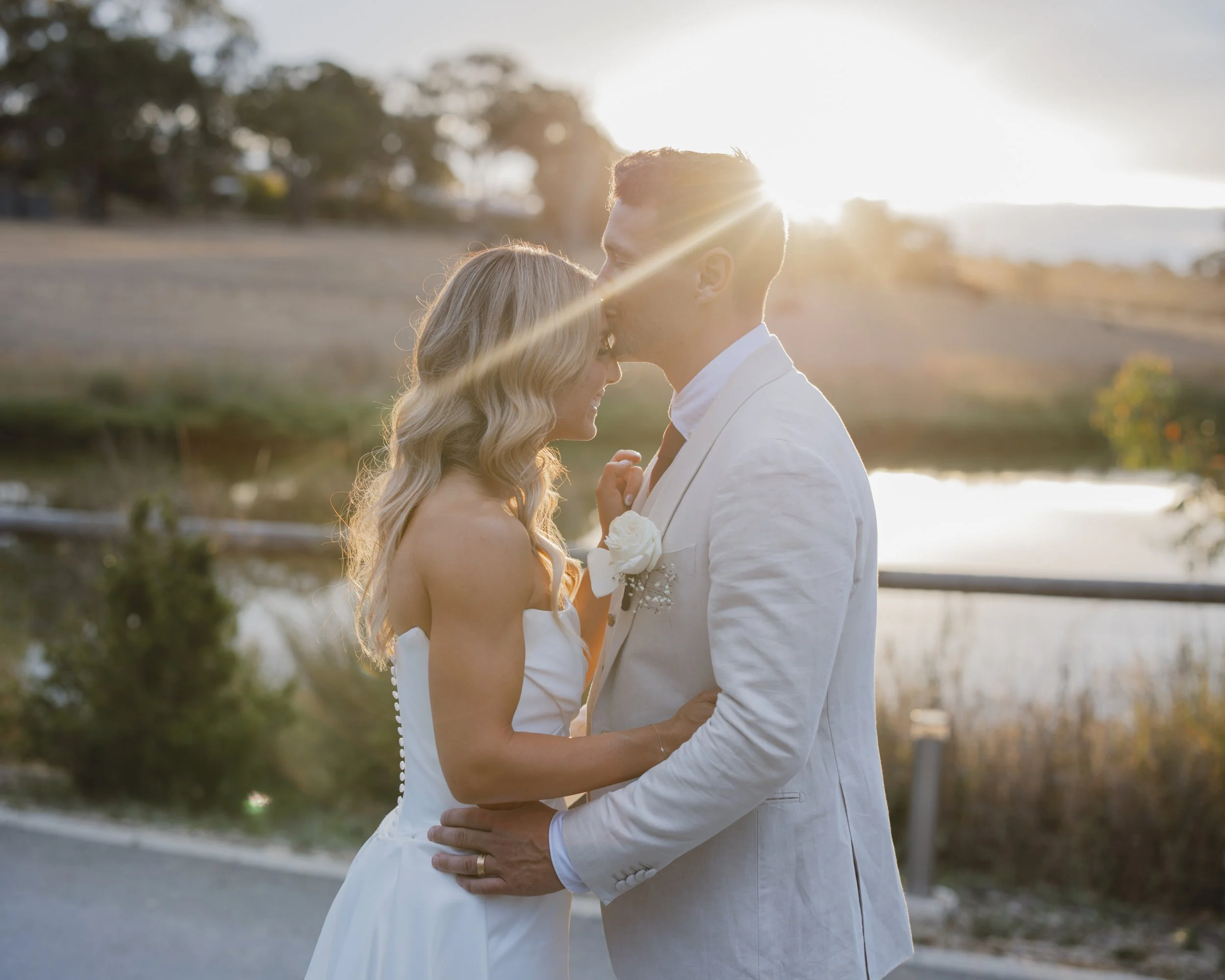 Newlyweds sharing a quiet moment beside the water at sunset during their Adelaide wedding.