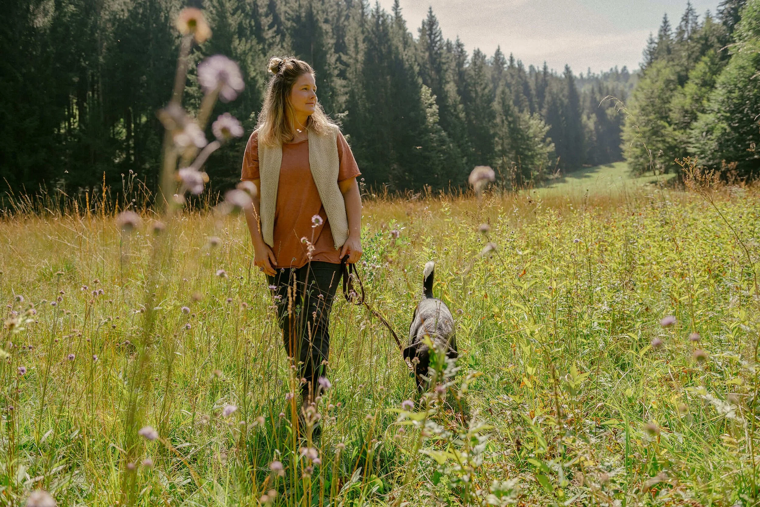 Mensch und Hund laufen Seite an Seite durch grünes Gras – Sinnbild für Miteinander und Bewegung.