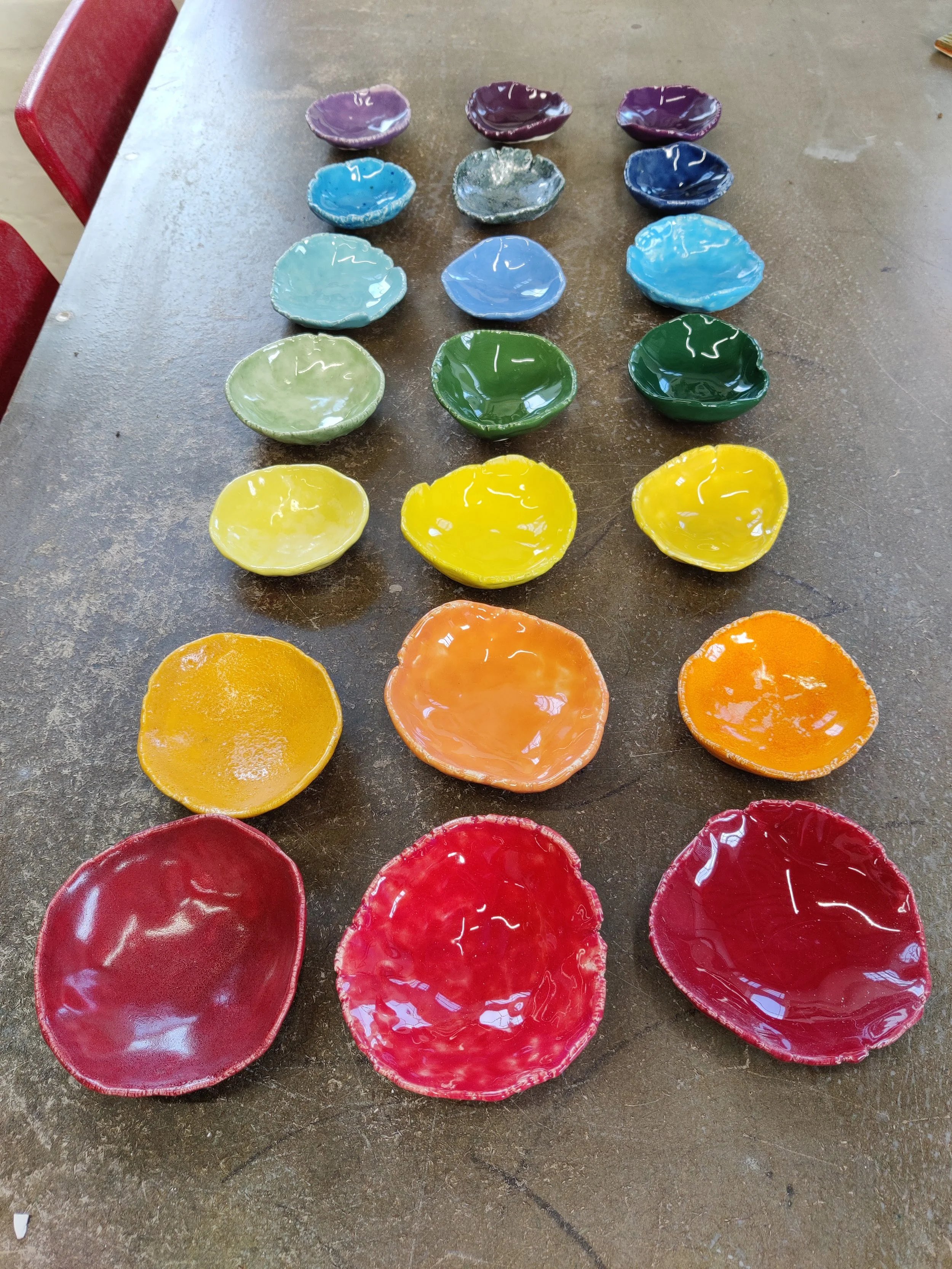 Small rainbow ceramic pots in three rows of seven inspired by the chakras