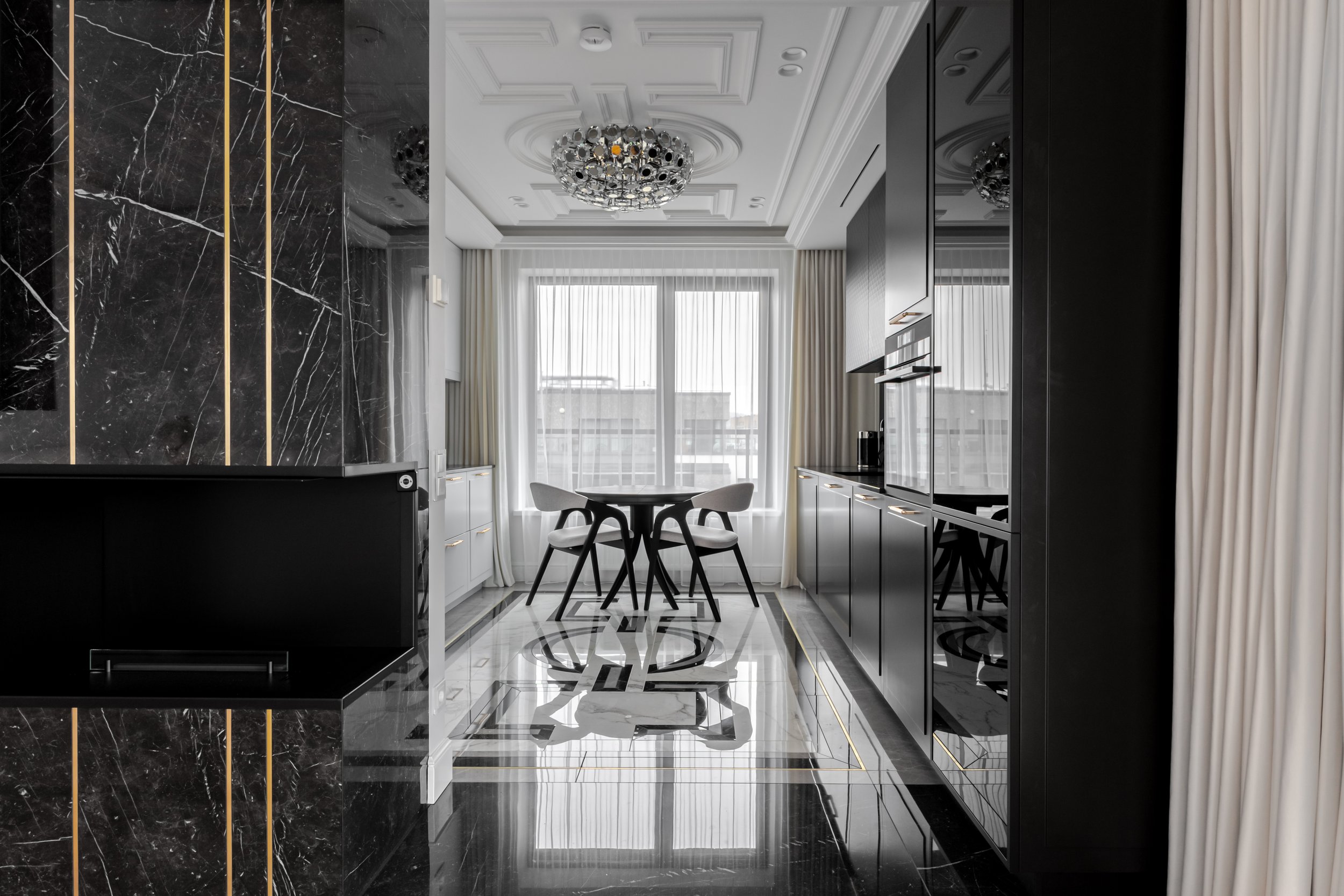 Modern dining area with black and white color scheme, marble flooring, a round black table with four chairs, large windows with sheer curtains, and a decorative ceiling light.