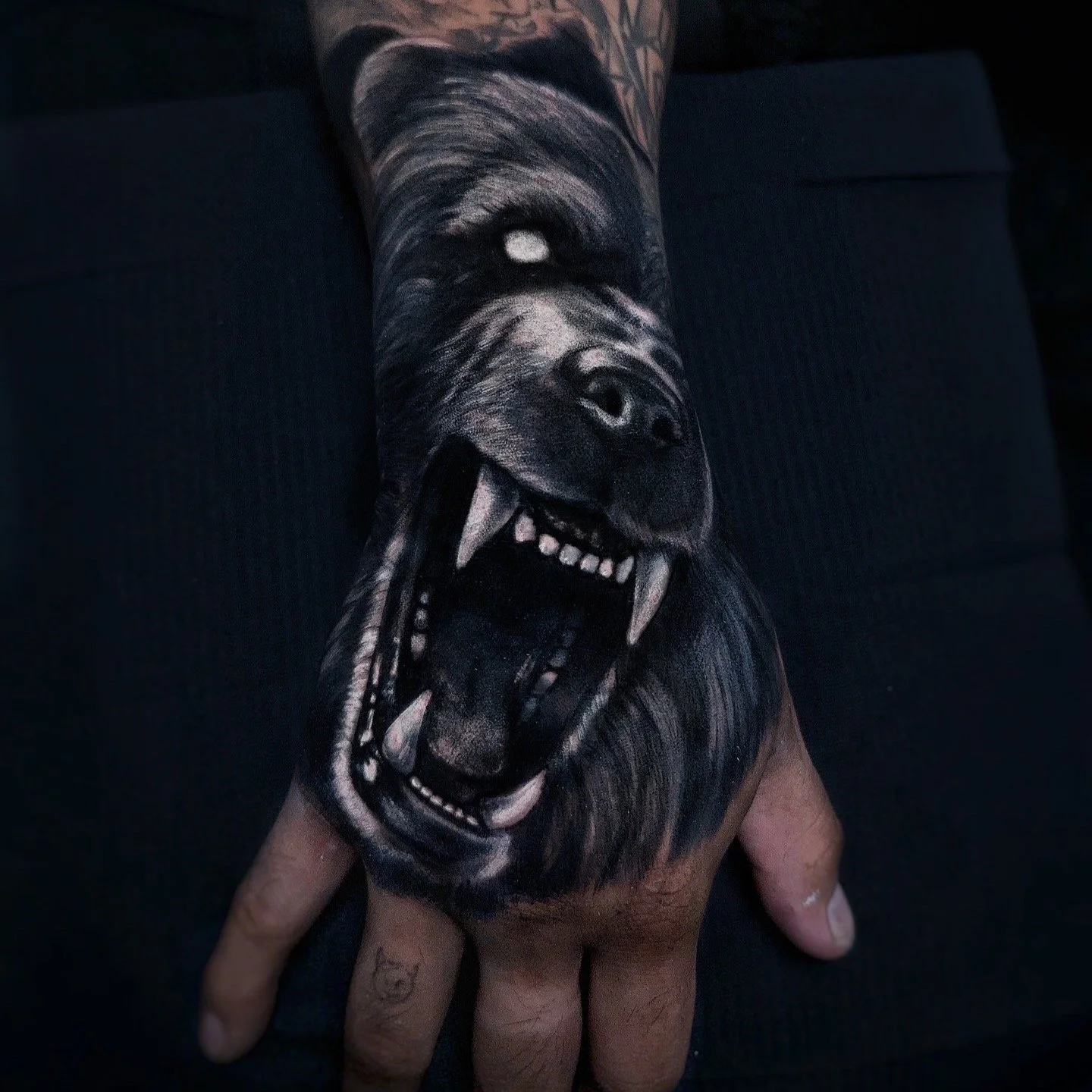 Dark style tattoo of a bear on a hand