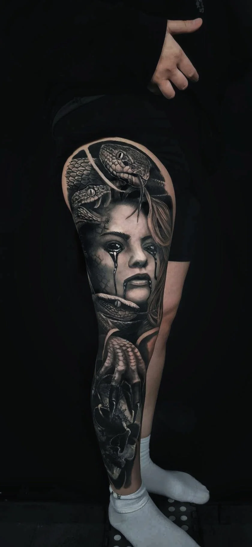 A dark realism tattoo of a Medusa on a tigh