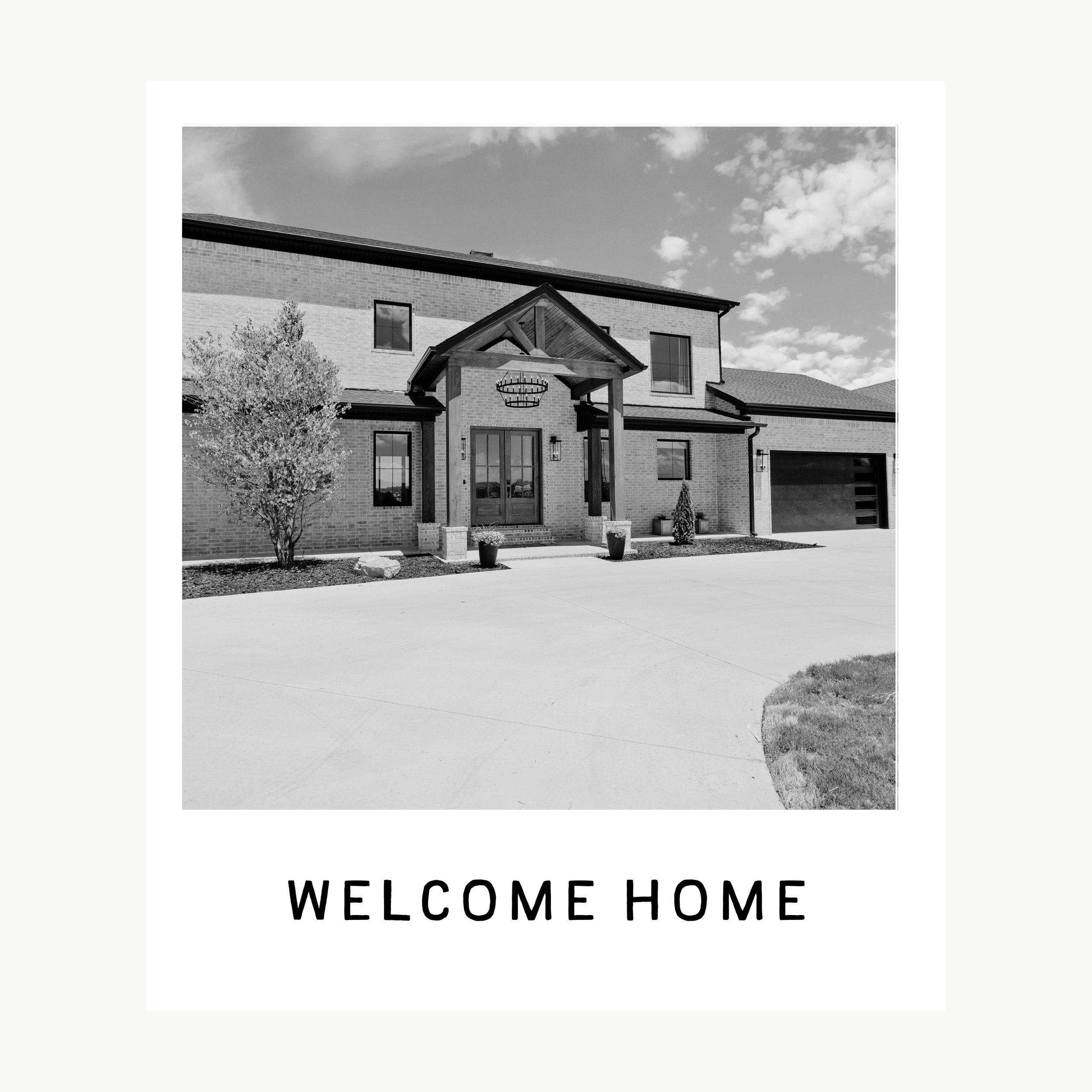 Black and white photo of a modern house with a welcoming front porch and a sign that says "Welcome Home" at the bottom.