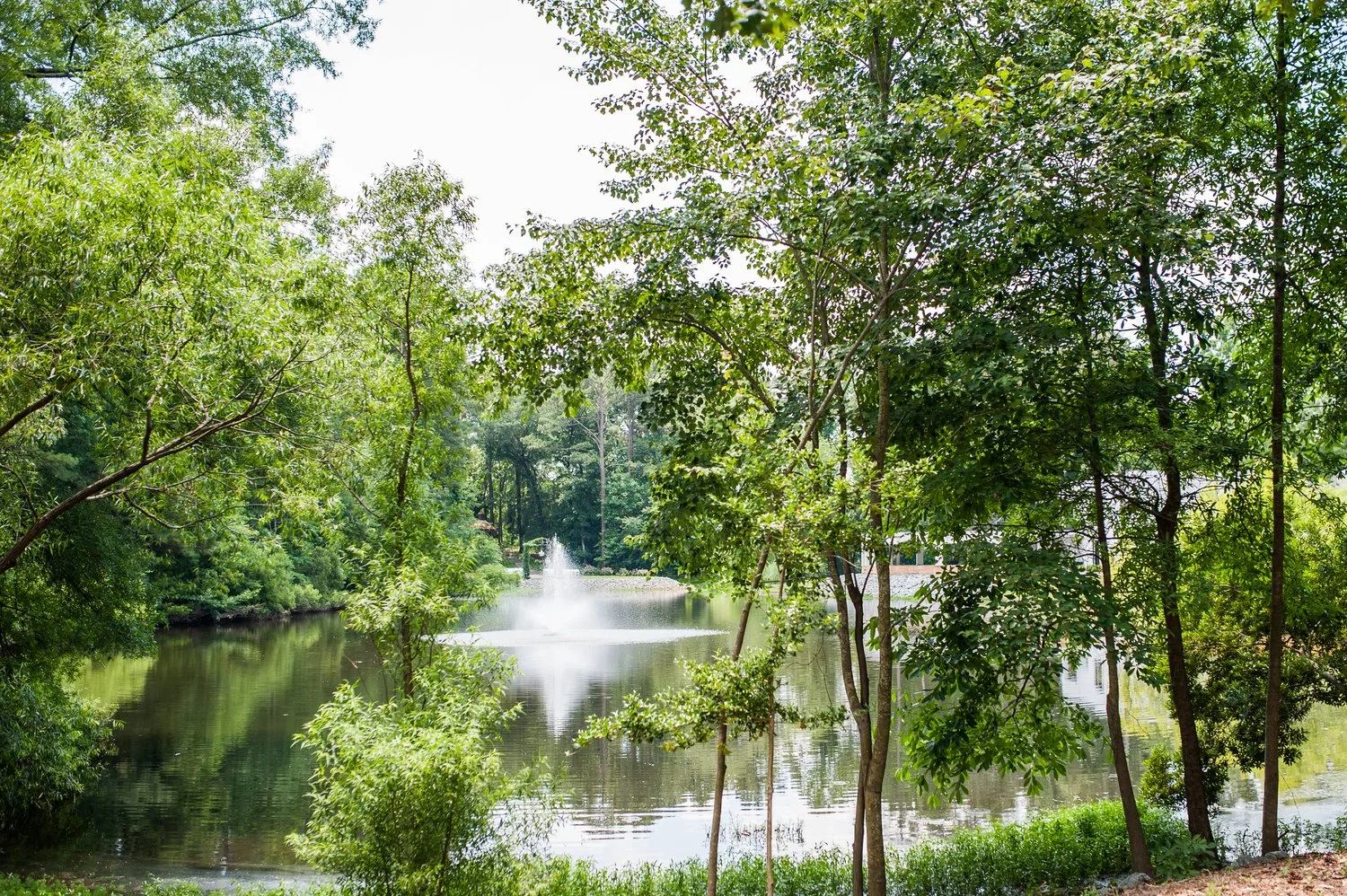 White building with columned tower and sloped roof, surrounded by trees and landscaping.