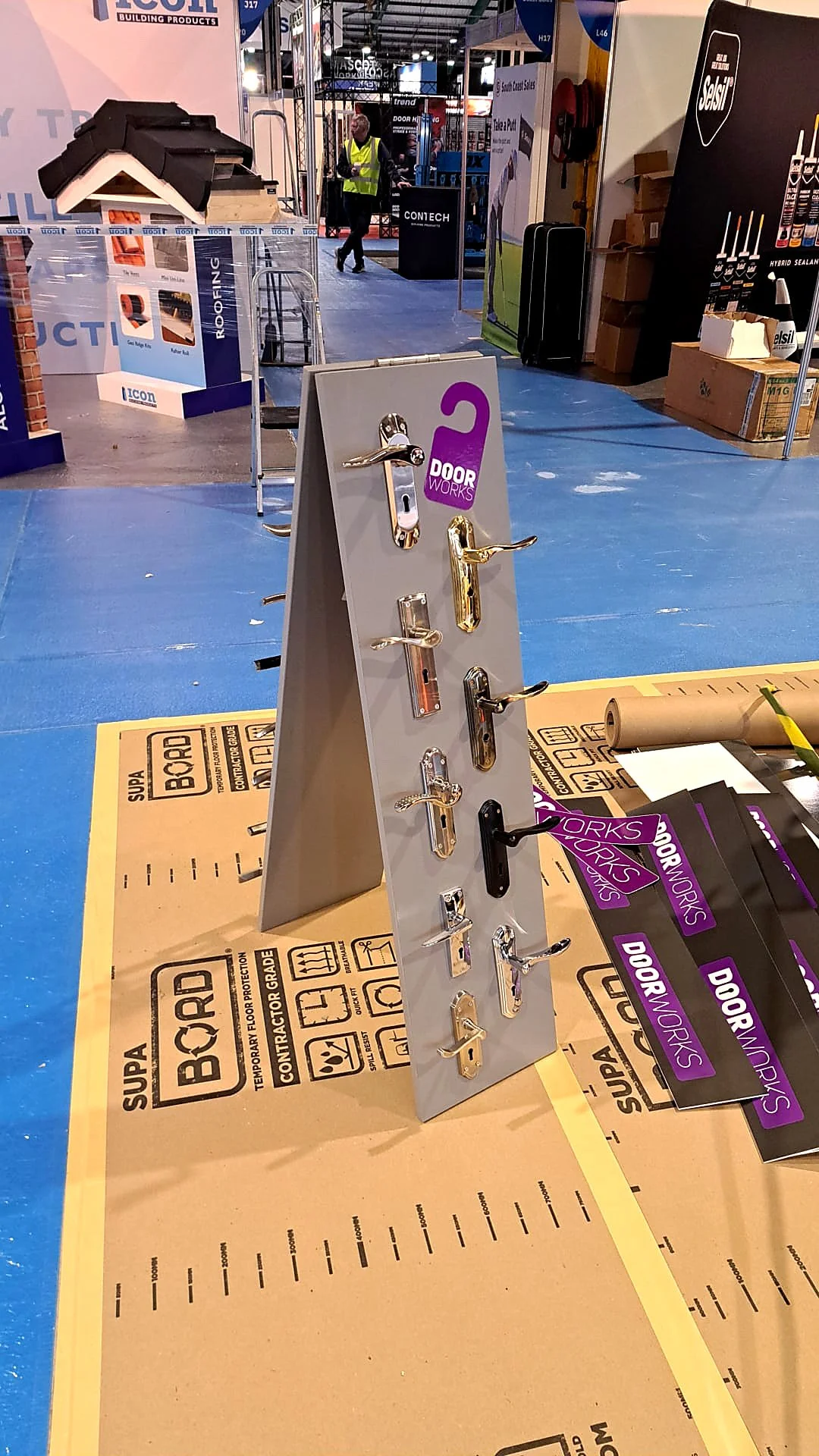 Display of various door handles on a gray stand at a trade show.