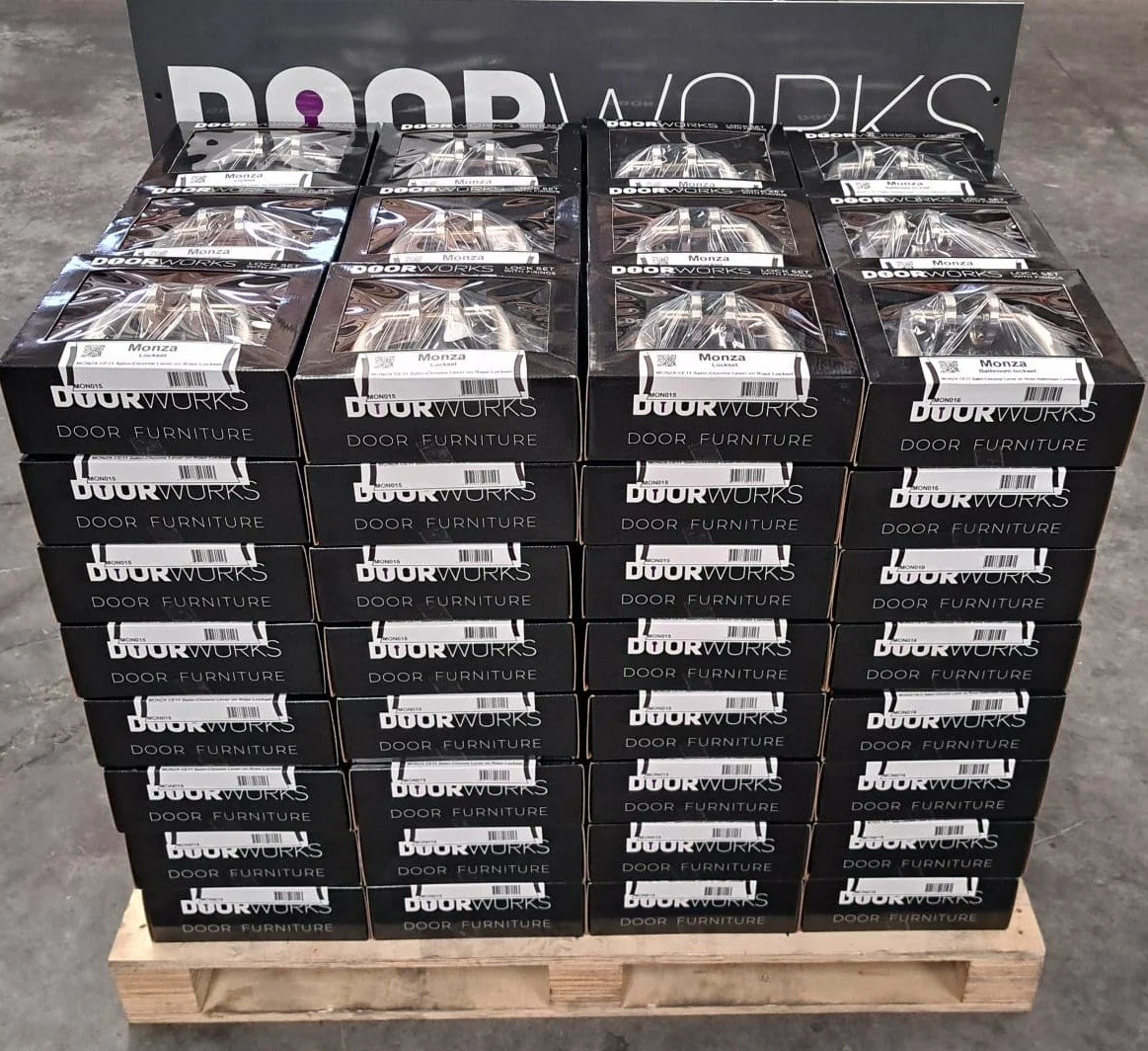 Stacked boxes of DOORWORKS door furniture on a wooden pallet.