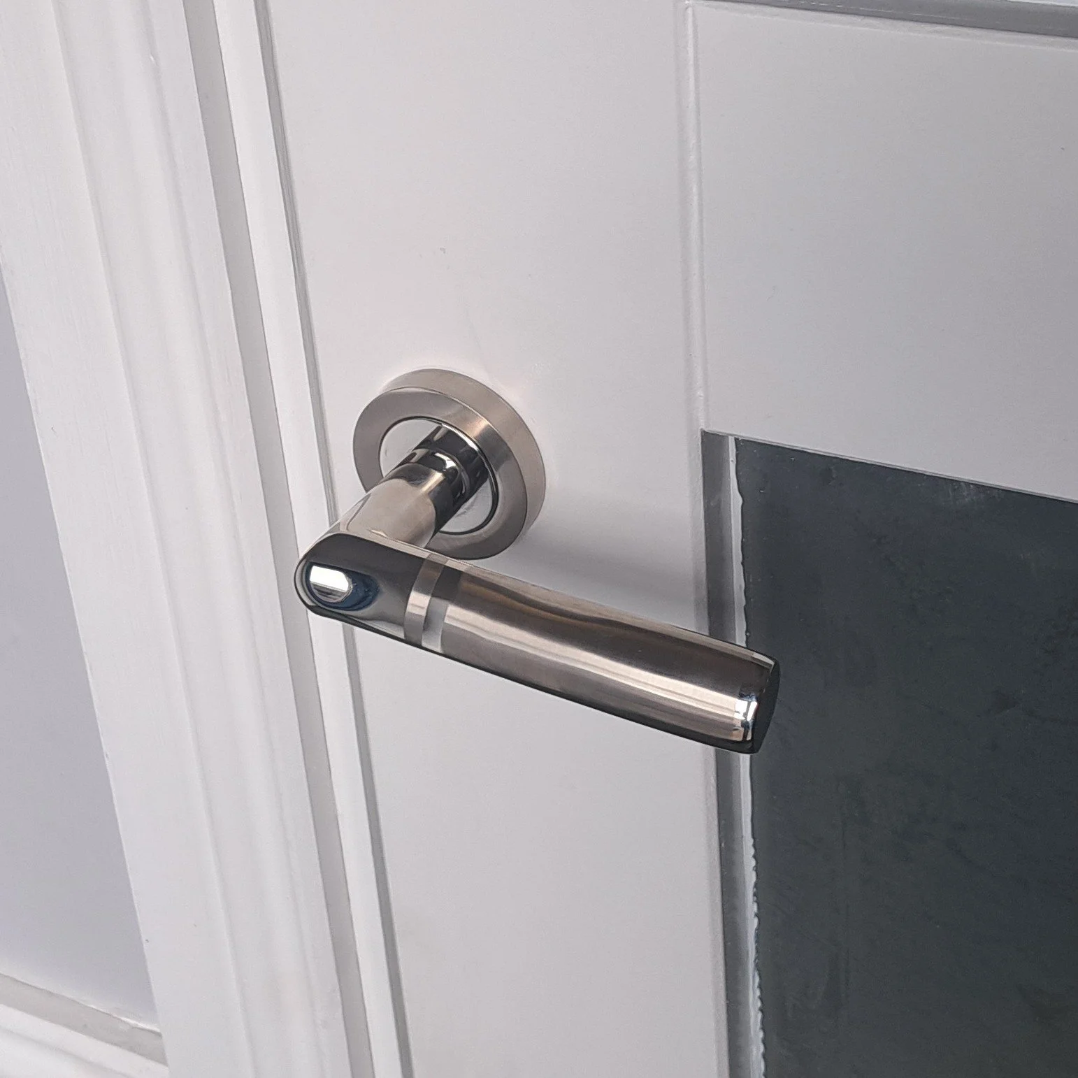 Close-up of a modern silver door handle on a white door.