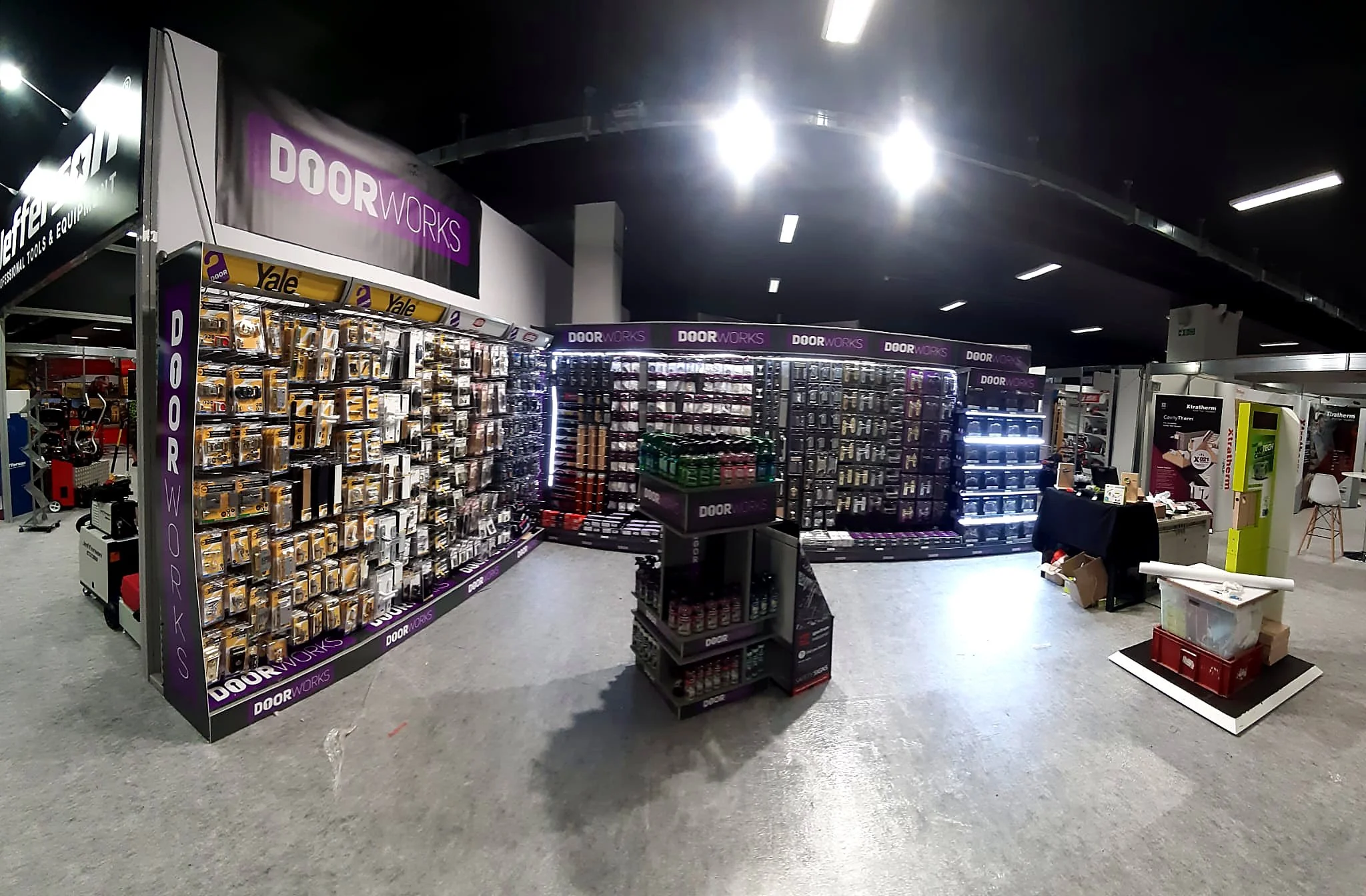 Indoor store display with hardware and door hardware products, including hinges and locks, on shelves labeled 'Door Works.'