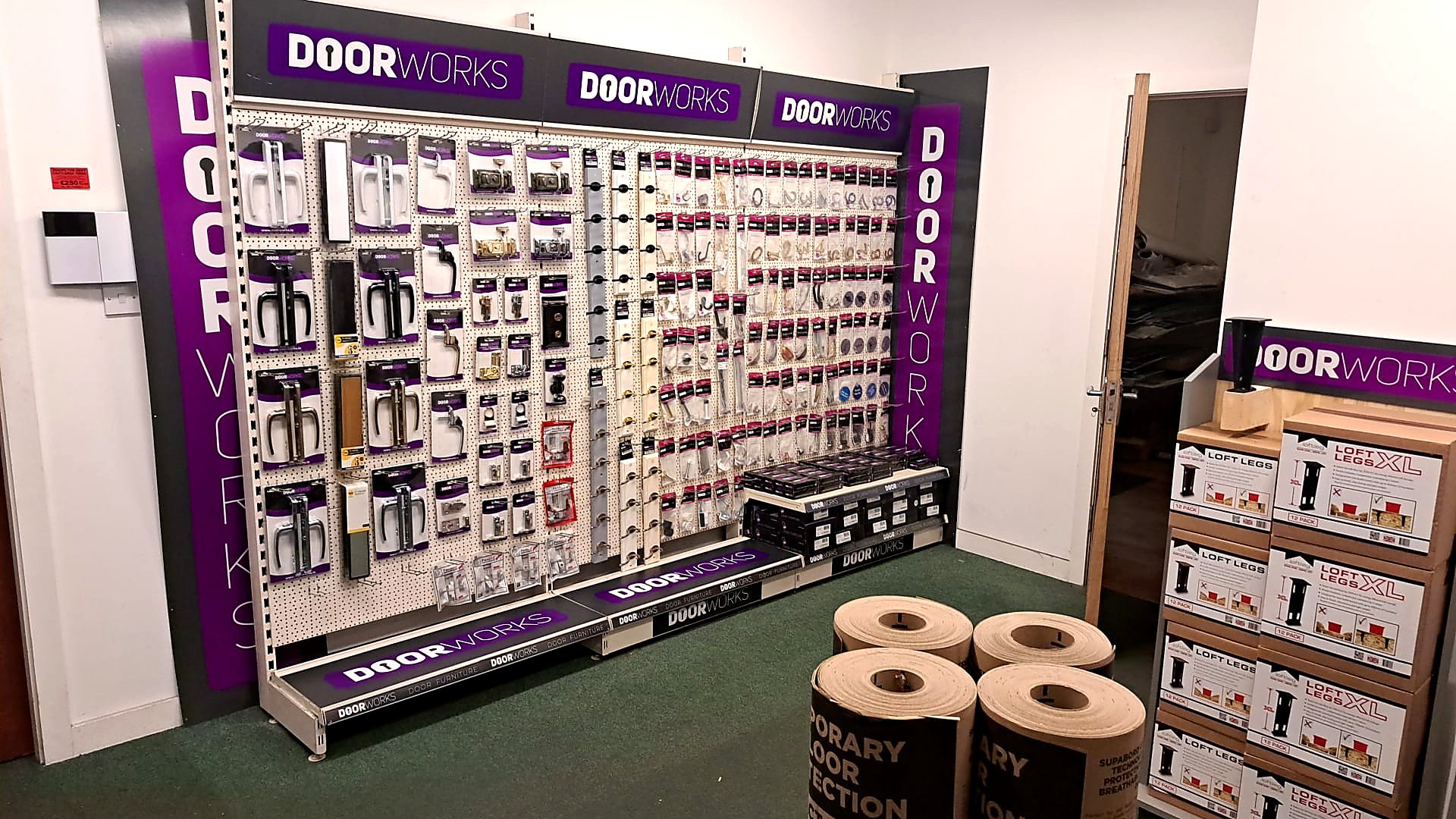 Display wall of door hardware and accessories at a hardware store, featuring handles, locks, and security products with the brand name 'Doorworks' prominently displayed.
