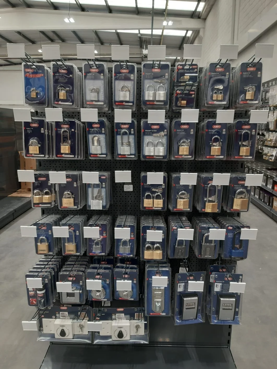 Display of various padlocks on a store pegboard, including combination, key, and digital locks.