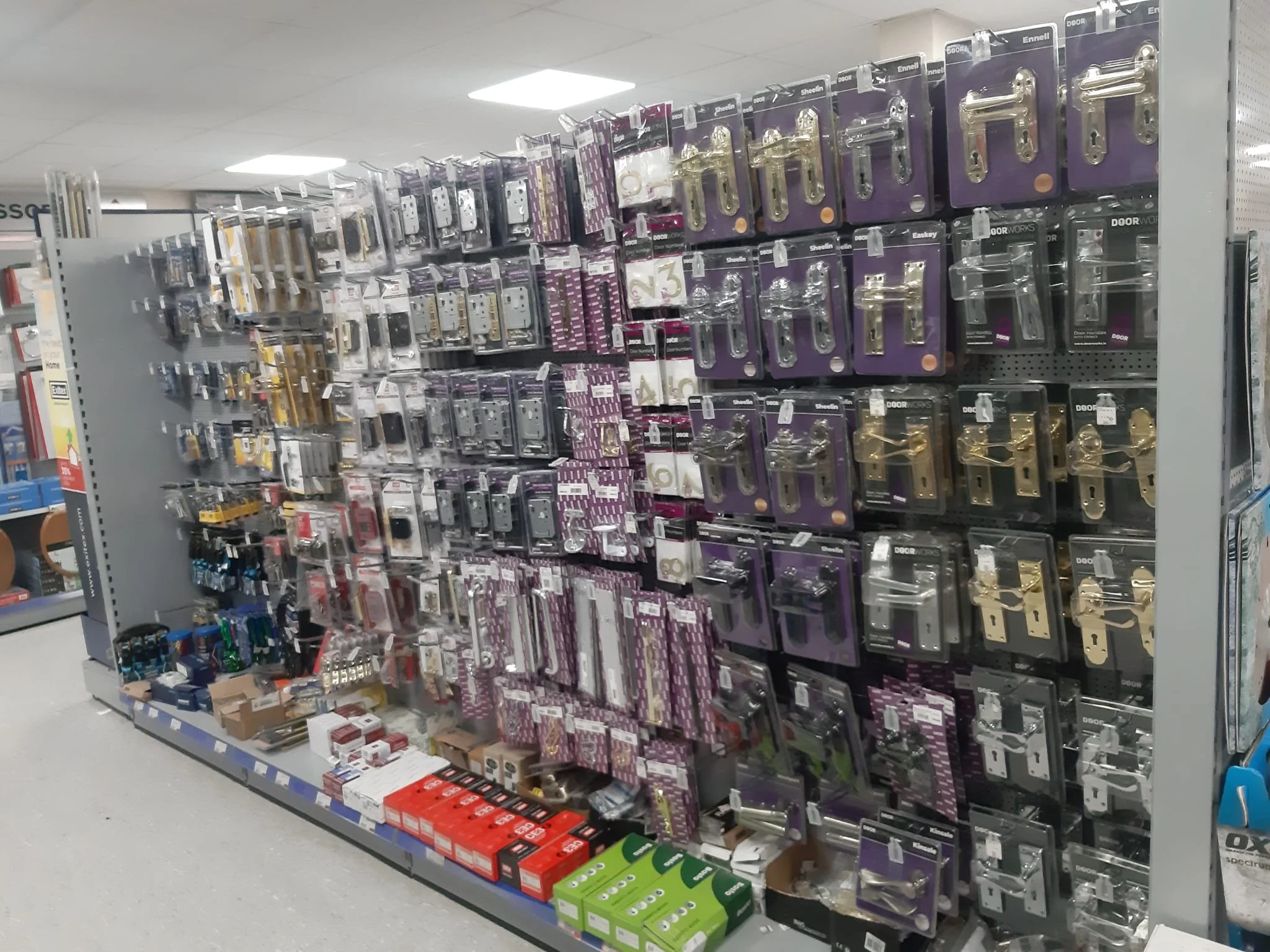 Store shelf displaying various door hardware, including door handles and locks, in packaging.