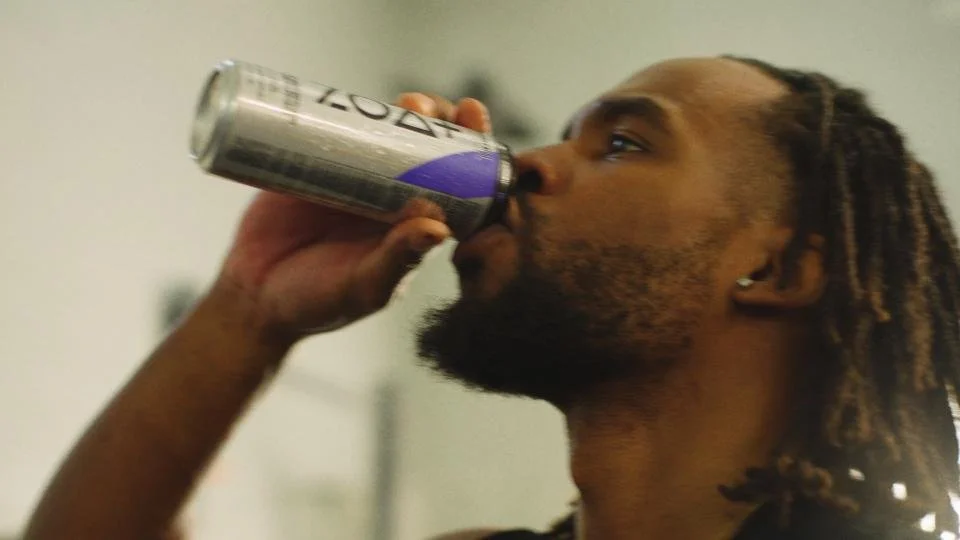 A man with dreadlocks drinking from a can of Zevia soda.