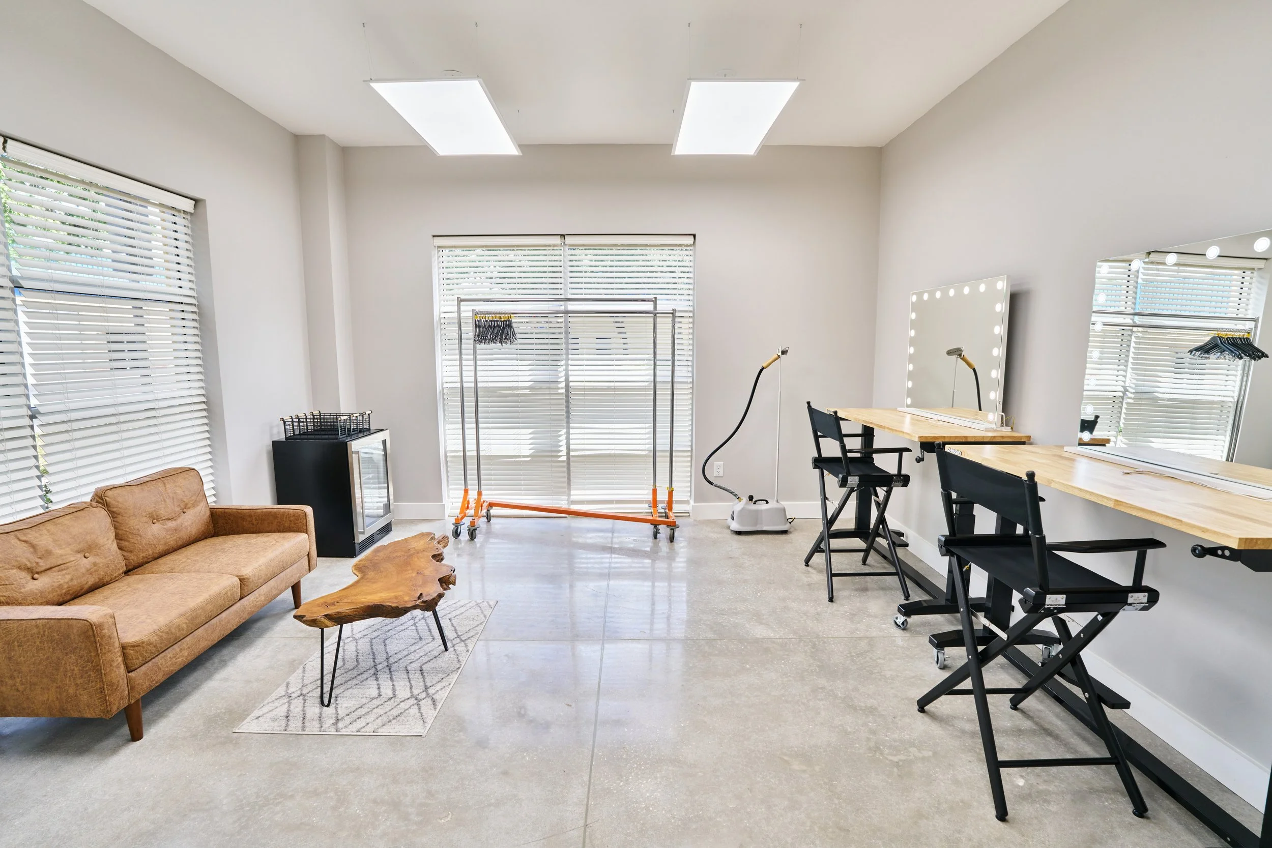 Professional green room and makeup station featuring lighted mirrors and comfortable lounge area at Go Bold Studio in Casselberry, FL, available for Orlando commercial production rentals.