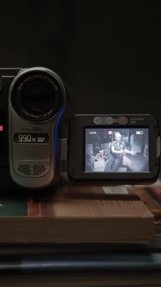 Digital camera recording a person sitting and gesturing while speaking.